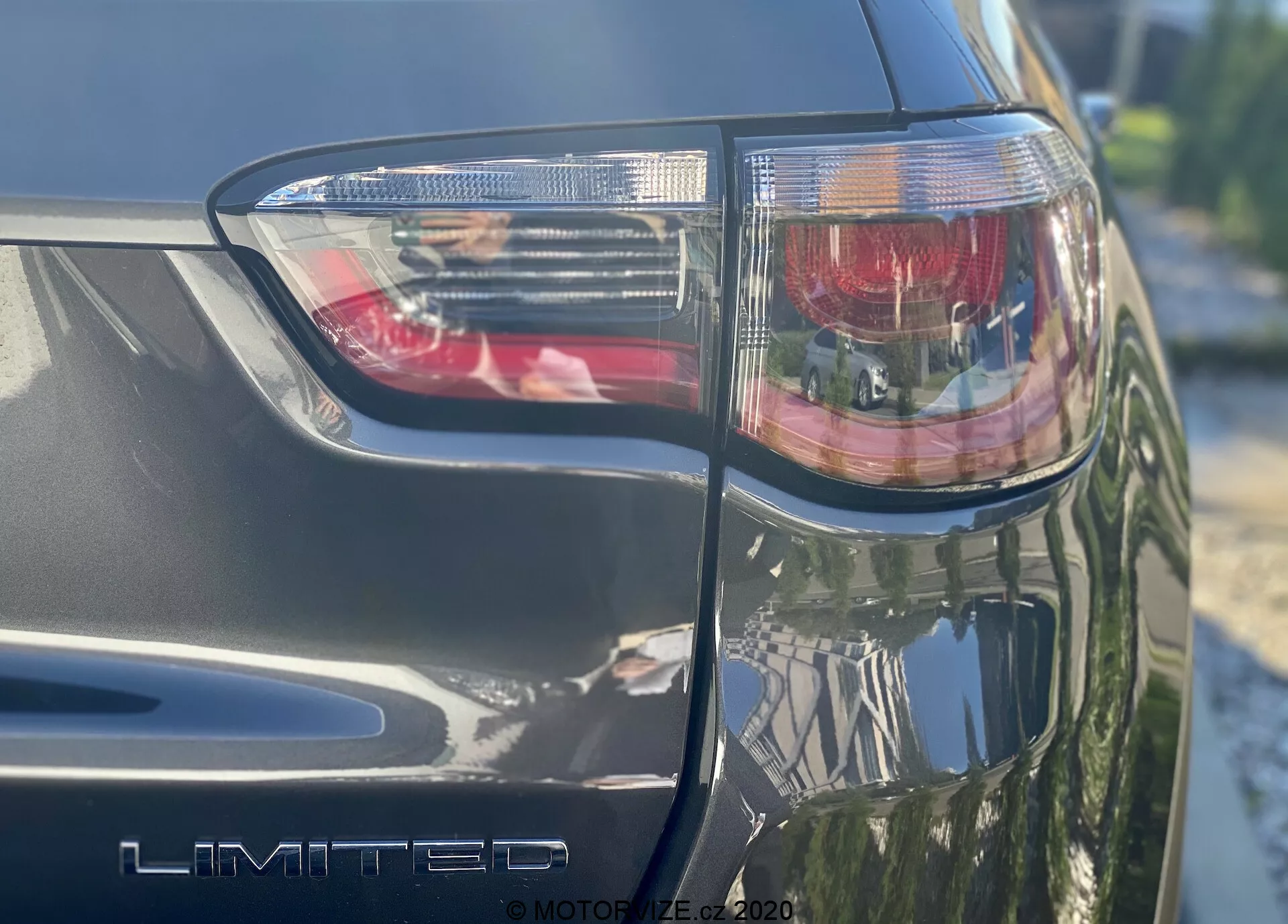 Un gros plan incliné du côté arrière gauche d'une Jeep Compass 2017, avec le bloc de feu arrière comprenant une lumière de frein rouge et des sections claires, affichant en premier plan le badge 'LIMITED'. La finition métallique et les angles vifs du design avec technologie d'éclairage LED sont visibles, photographiés par une journée ensoleillée.