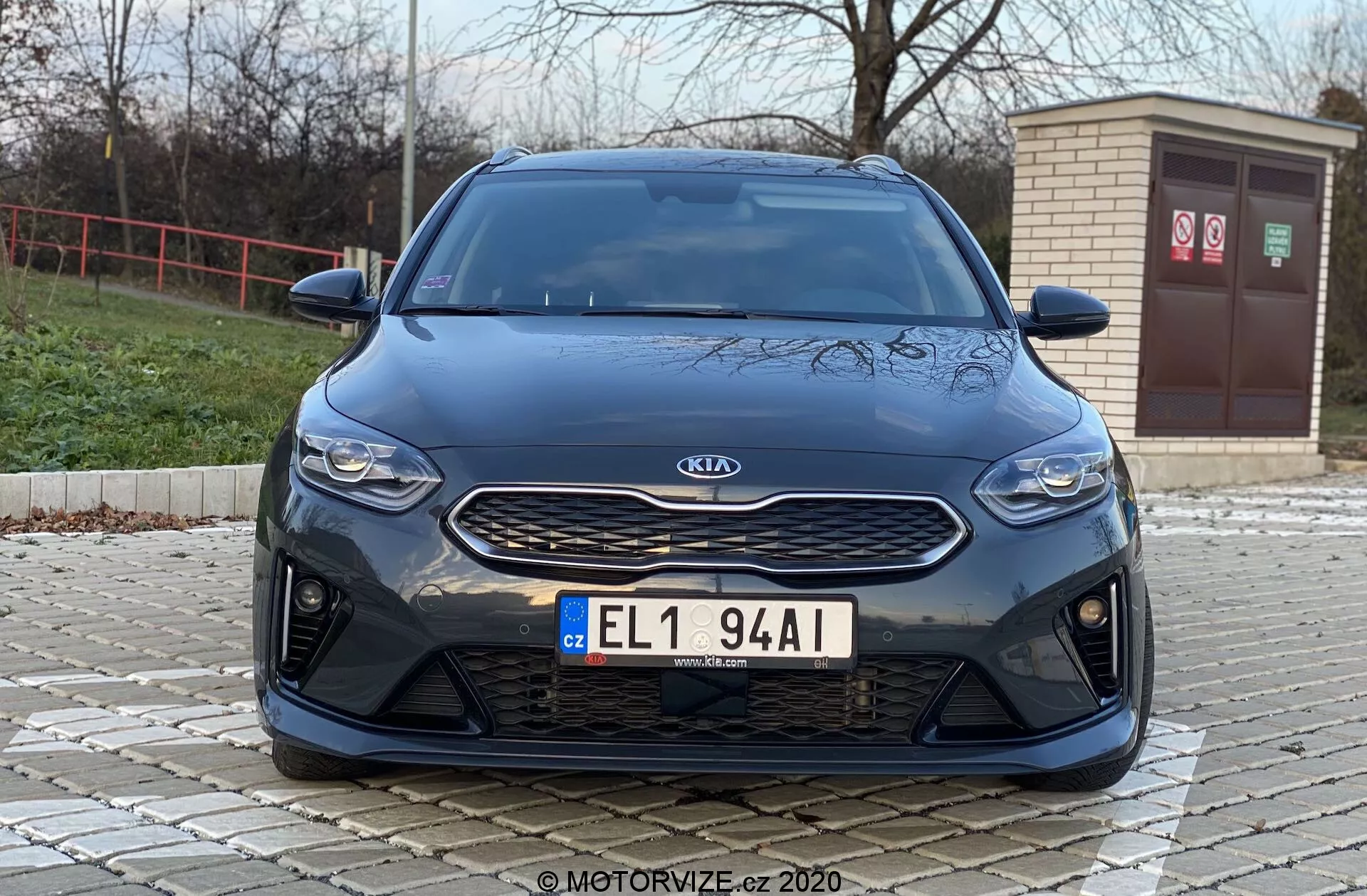 Vue avant d'une Kia Ceed 2018 depuis un angle bas, mettant en valeur les éléments frontaux comme la calandre, les phares et le pare-chocs avec une esthétique moderne. L'image met en avant le badge argenté Kia sur une calandre noire texturée, les phares horizontaux élégants et le pare-chocs avant avec de grandes entrées d'air, suggérant des caractéristiques de performance sportive ou un refroidissement avancé par flux d'air.