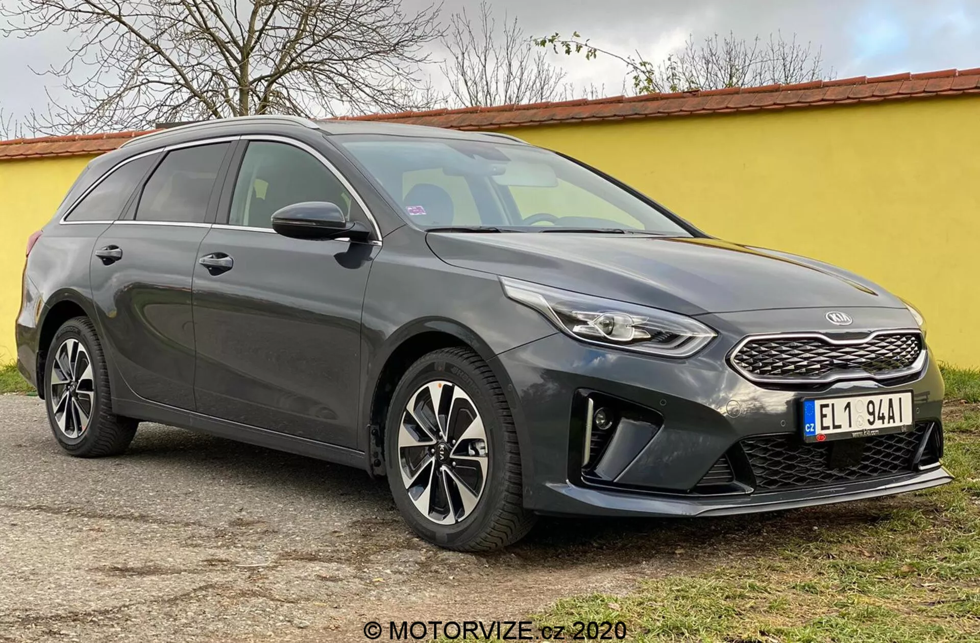 L'image présente la Kia Ceed 2018, un break moderne capturée sous un angle trois quarts avant, mettant en valeur sa face avant, comprenant une calandre structurée avec un emblème de marque distinctif, des phares étroits s'étendant vers l'arrière avec des feux de jour à LED et un pare-chocs avant avec des logements pour feux antibrouillard et des capteurs de stationnement. Les lignes élégantes du capot mènent à un pare-brise fortement incliné, accentuant le profil aérodynamique de la voiture. Les jantes en alliage à plusieurs branches et les rétroviseurs latéraux avec clignotants intégrés sont visibles, ainsi que la ligne de toit en pente vers l'arrière et les barres de toit, mettant en évidence à la fois le style et l'utilité. Les vitres teintées et les lignes de carrosserie le long du côté ajoutent une apparence sculptée. La voiture est stationnée sur une surface plane en extérieur.