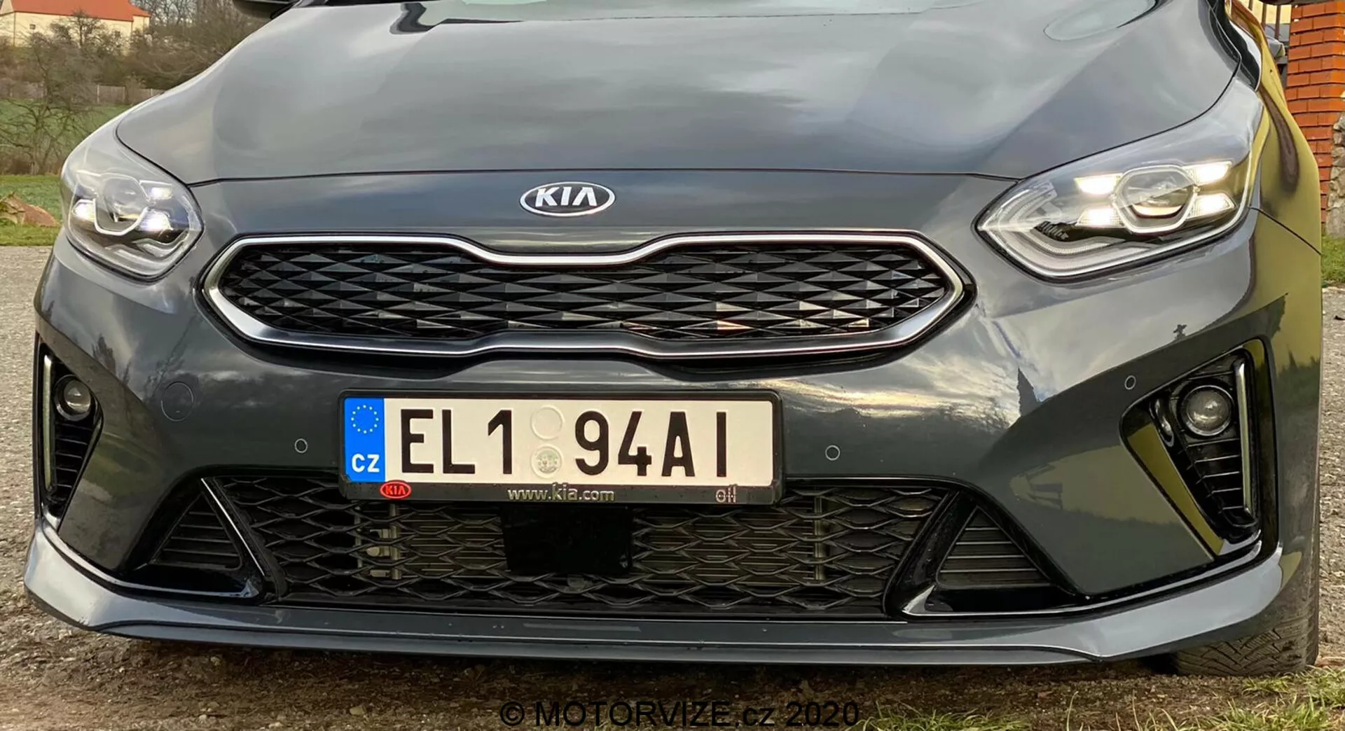 Cette image montre l'avant d'un véhicule Kia Ceed 2018 prise sous un angle bas. Elle met en évidence les phares à LED horizontaux et élégants, la calandre en treillis alvéolé avec un emblème Kia centré, la plaque d'immatriculation européenne de la République tchèque et le pare-chocs avant sportif avec de grandes ouvertures. La vue rapprochée met en évidence les capteurs de stationnement sous la calandre. Le design sportif suggère un niveau de finition haute performance, bien que les spécifications exactes ne soient pas claires. L'image haute résolution capture les détails et les contours du design, avec un angle légèrement décentré vers la gauche.