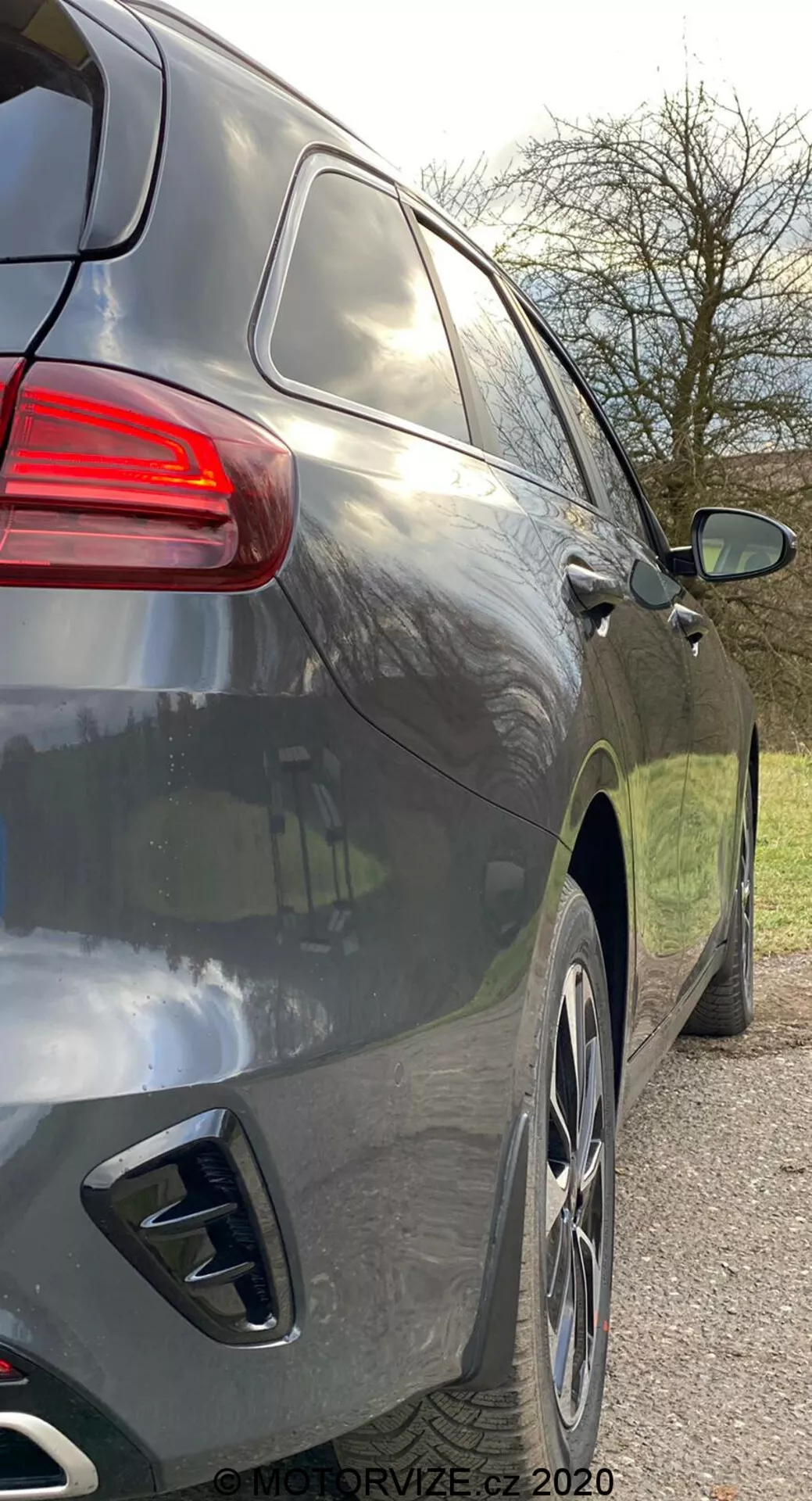 Gros plan sur la vue latérale droite d'un SUV moderne d'une perspective légèrement arrière montrant la partie arrière et le profil latéral de la poignée de porte arrière aux feux arrière, avec des lignes aérodynamiques lisses, une peinture métallique foncée, des grandes jantes en alliage, des doubles embouts d'échappement, des vitres teintées et un feu arrière au design contemporain.