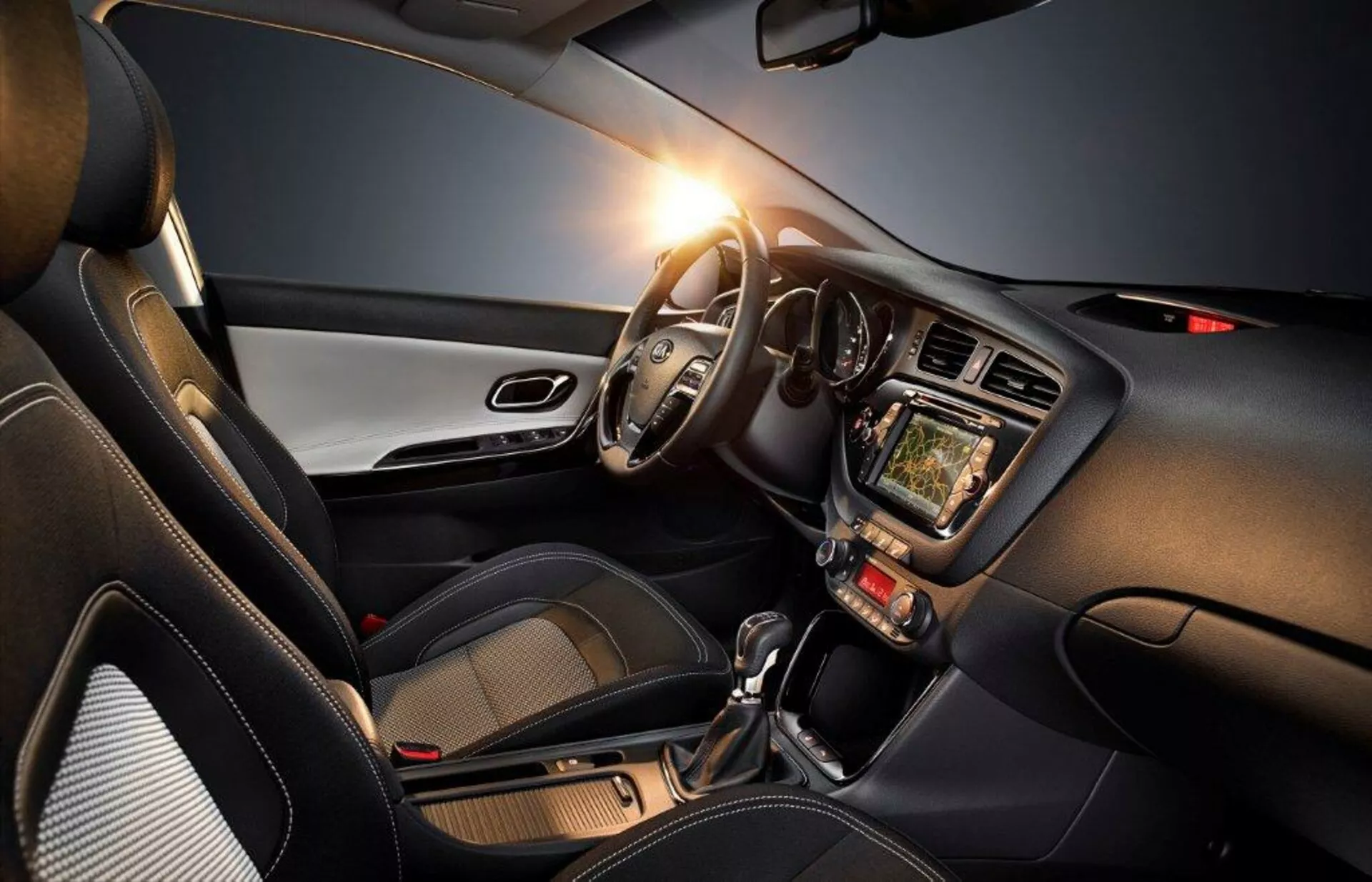 Intérieur de la Kia Cee'd 2009 mettant en avant le côté conducteur avec volant à gauche, tableau de bord, système d'infodivertissement tactile, commandes de climatisation, levier de vitesse automatique et accents de design moderne, soulignant la technologie, le confort et un aspect sportif