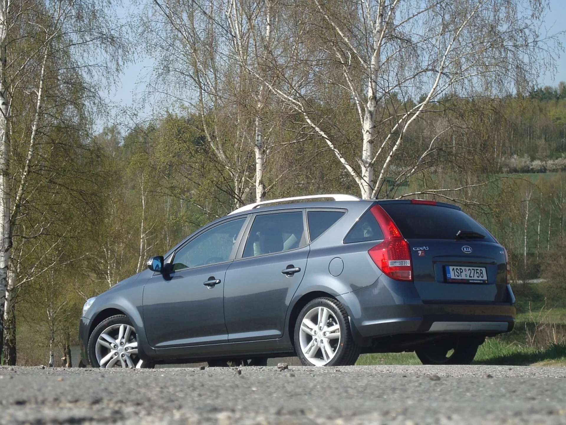 Kia Ceed break 2009 en gris, présentant le design latéral et arrière, avec un focus sur la ligne de toit aérodynamique, les feux arrière et la fenêtre arrière, garée à l'extérieur