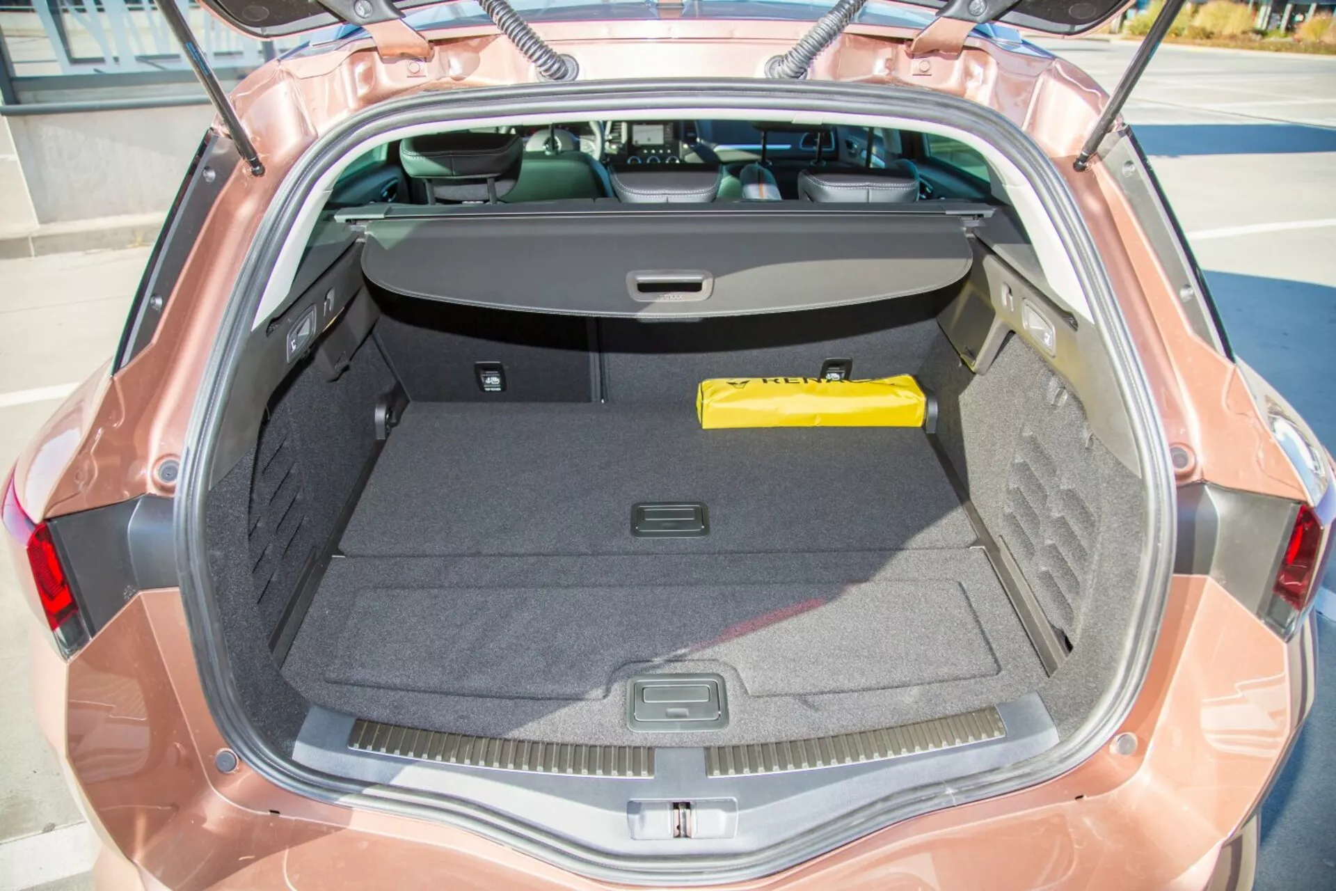 Vue rapprochée de l'espace de coffre de la Kia cee'd 2009 depuis un angle supérieur montrant l'intérieur, le couvercle ouvert et le pare-brise arrière partiellement avec couverture de chargement rétractable, soulignant la spaciosité et les fonctionnalités de rangement.