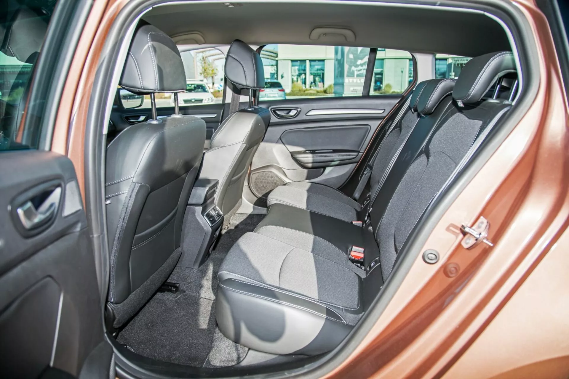Intérieur du Kia Ceed 2009 montrant la banquette arrière bicolore avec un siège rabattu vers l'avant pour le chargement, ceintures de sécurité, appuie-têtes, commandes des vitres électriques et haut-parleur de porte, mettant en avant les sièges flexibles et le design de luxe