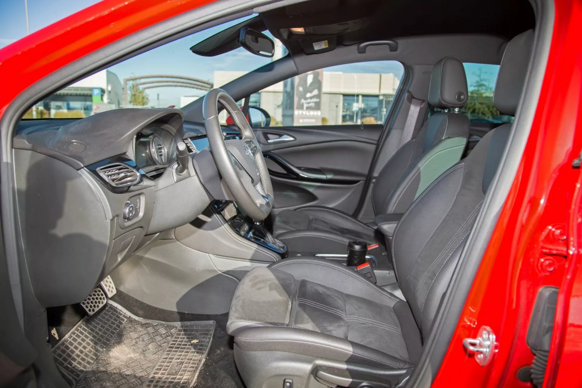 Intérieur de la Kia cee'd 2009 montrant le volant avec commandes, écran d'infodivertissement central, cluster d'instruments visible, console centrale avec commandes supplémentaires, sièges tapissés avec appuie-têtes, intérieur de porte détaillé avec commandes, schéma de couleurs bicolore, vue du rétroviseur et du miroir côté conducteur, tapis résistants et signaux d'indicateurs d'airbag, capturant un design complet et des caractéristiques axées sur la technologie depuis une perspective latérale extérieure