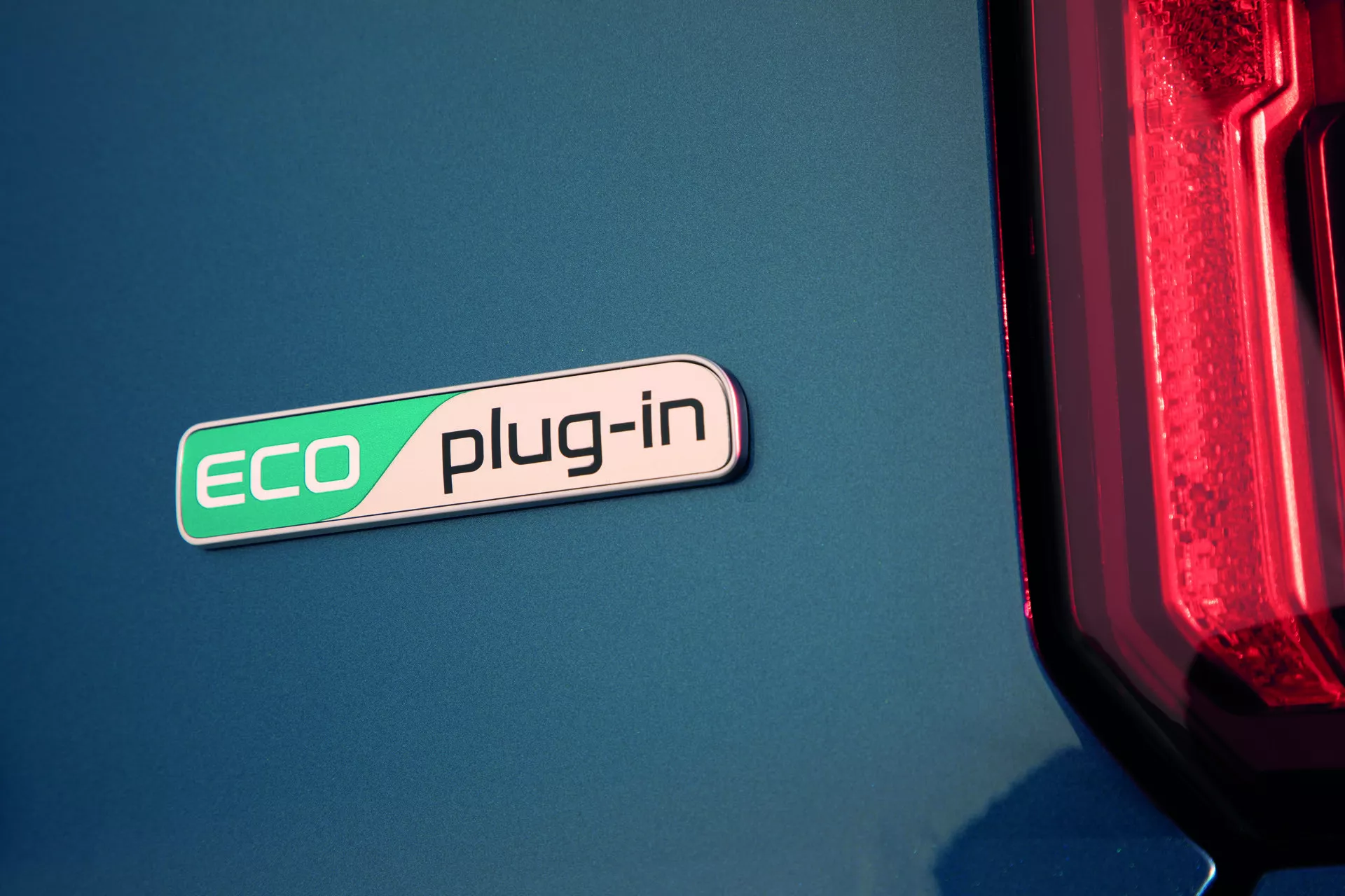 Gros plan sur le badge ECO plug-in de la Kia Sorento 2020 (MQ4) mettant en avant la technologie hybride sur une carrosserie bleue avec un aperçu du feu arrière LED moderne