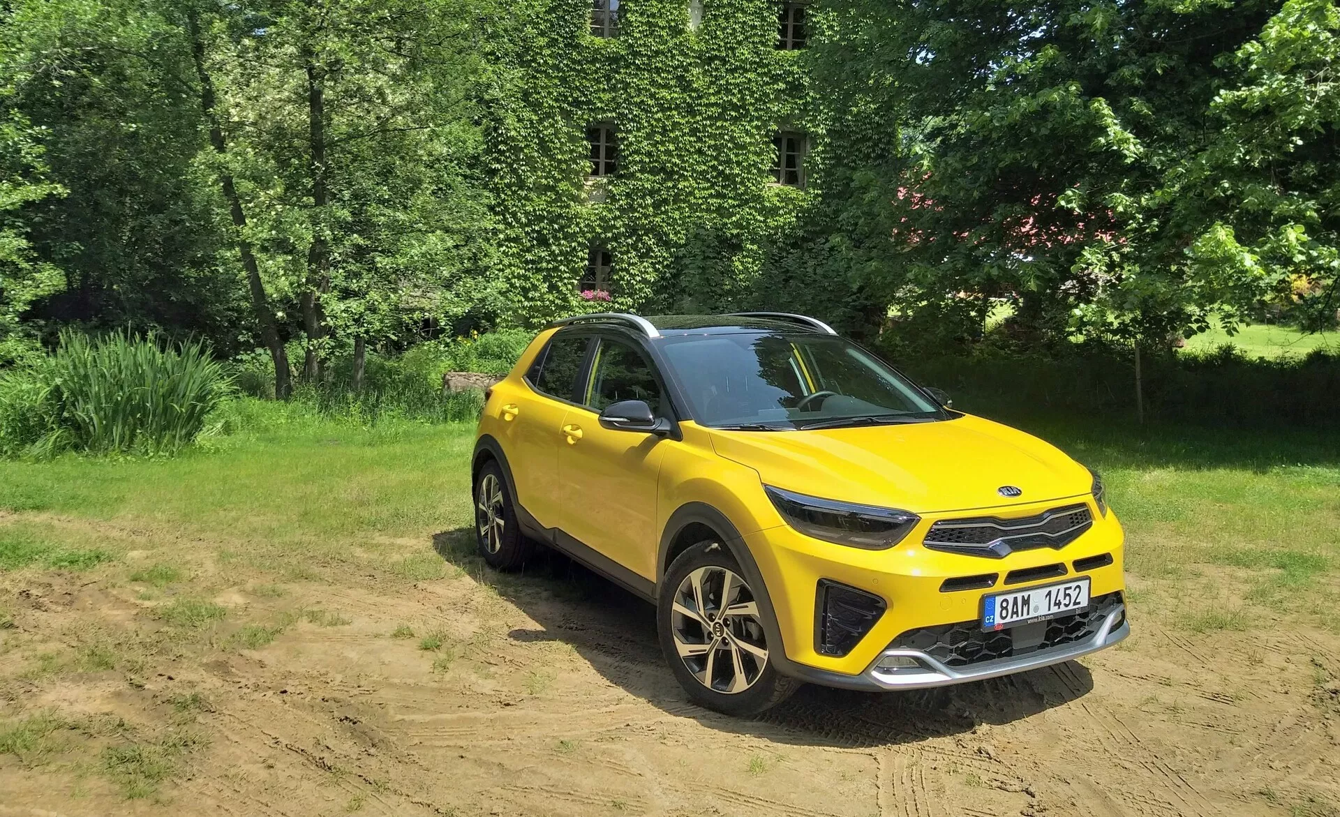 SUV crossover jaune vibrant Kia Stonic 2017 en vue avant trois quarts mettant en lumière sa grille avant, phares LED, capot et côté conducteur, situé contre un arrière-plan naturel avec lumière solaire sur terrain dégagé, démontrant des capacités hors route, jantes alliage sportives et éléments de conception moderne.