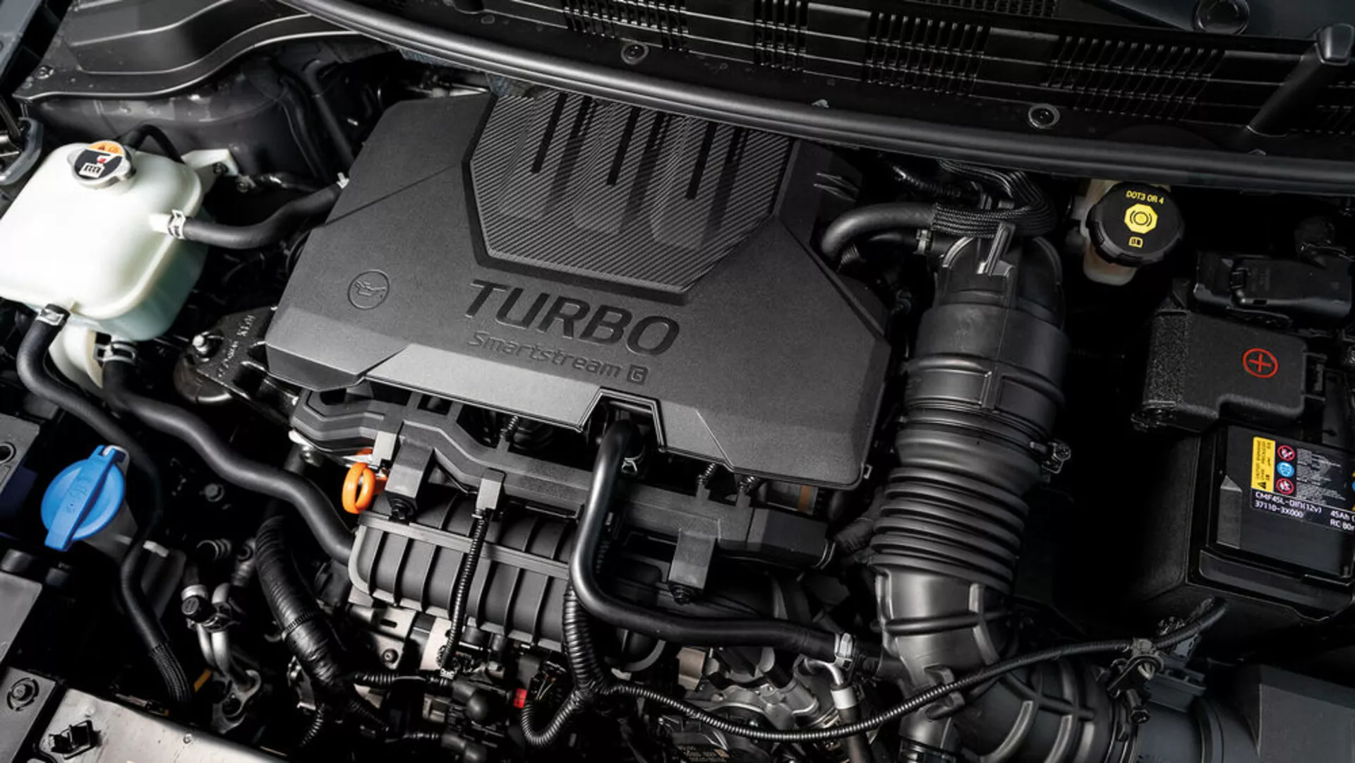 Vue rapprochée du compartiment moteur du Kia Stonic 2017 avec couvercle de moteur turbocompressé et divers composants mécaniques visibles, montrant les aspects technologiques du véhicule