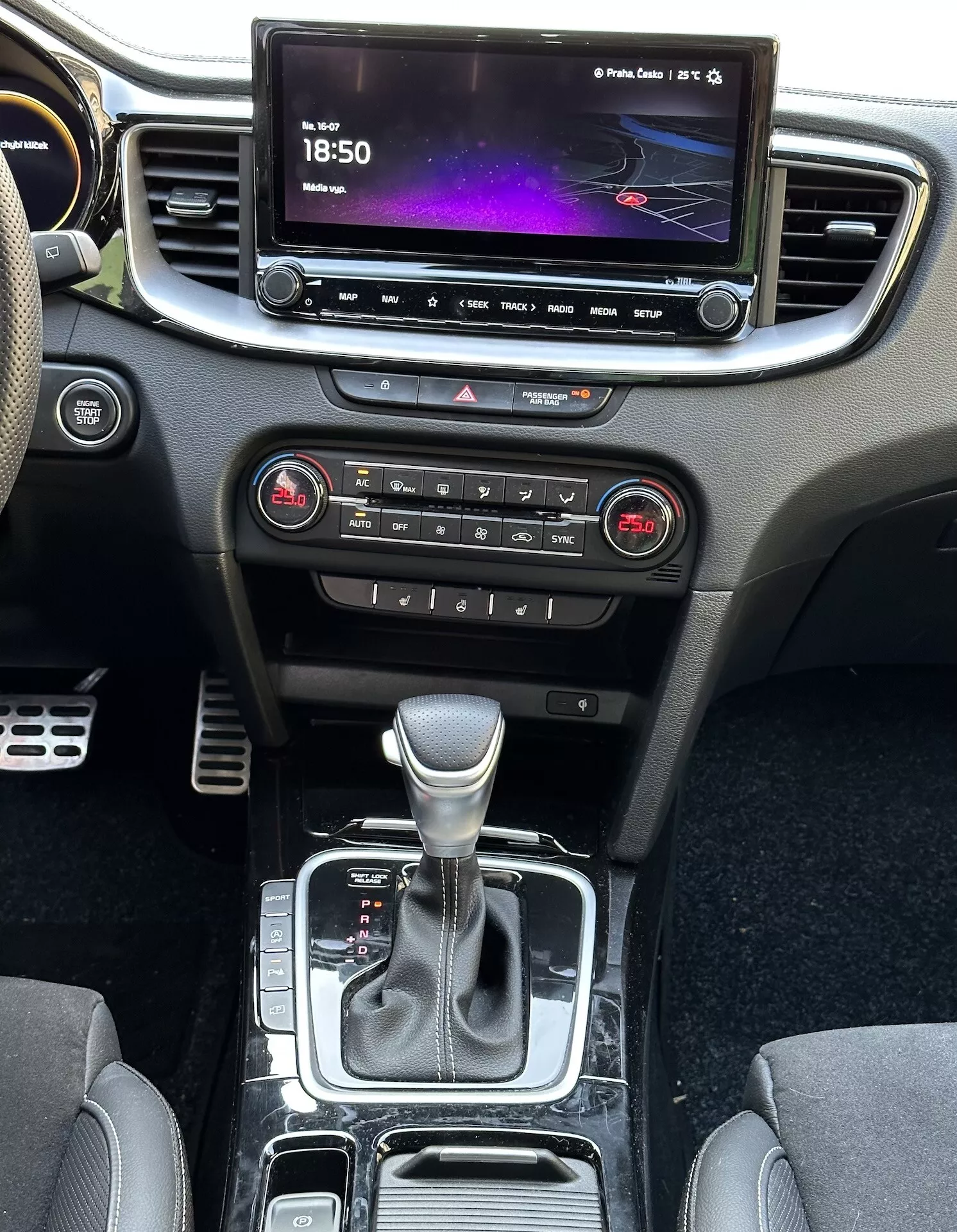 Vue intérieure de la Kia Xceed 2022 montrant la console centrale, le tableau de bord, l'écran d'infodivertissement, les boutons de contrôle climatique, le levier de vitesse et les zones de rangement, soulignant la technologie moderne et le design du véhicule.