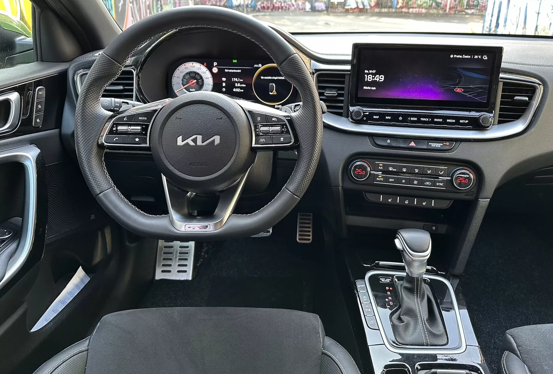 Vue intérieure du Kia XCeed 2022 mettant en évidence les caractéristiques centrées sur le conducteur telles qu'un volant multifonction en cuir avec boutons multimédia et régulateur de vitesse, un tableau de bord numérique, un grand système d'infodivertissement tactile, des commandes automatiques de climatisation, un levier de vitesse automatique, des sièges avec une garniture bicolore et des pédales sport en métal d'une perspective à la première personne.