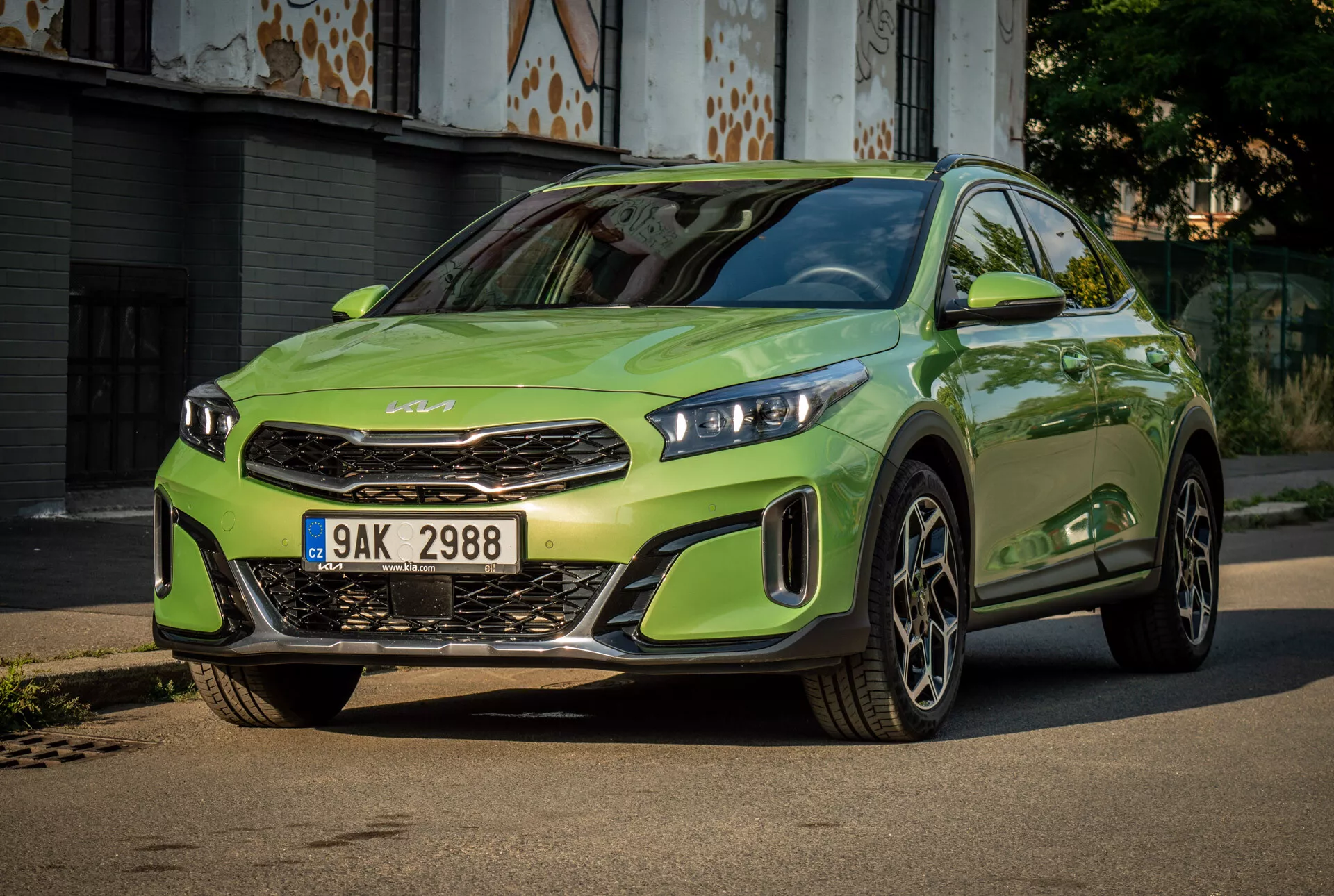 Kia XCeed 2022 en vert lime vibrant avec phares LED, calandre avant proéminente avec emblème de la marque, pare-chocs avant sportif et grandes roues en alliage, centrée sur une route pavée avec un fond urbain