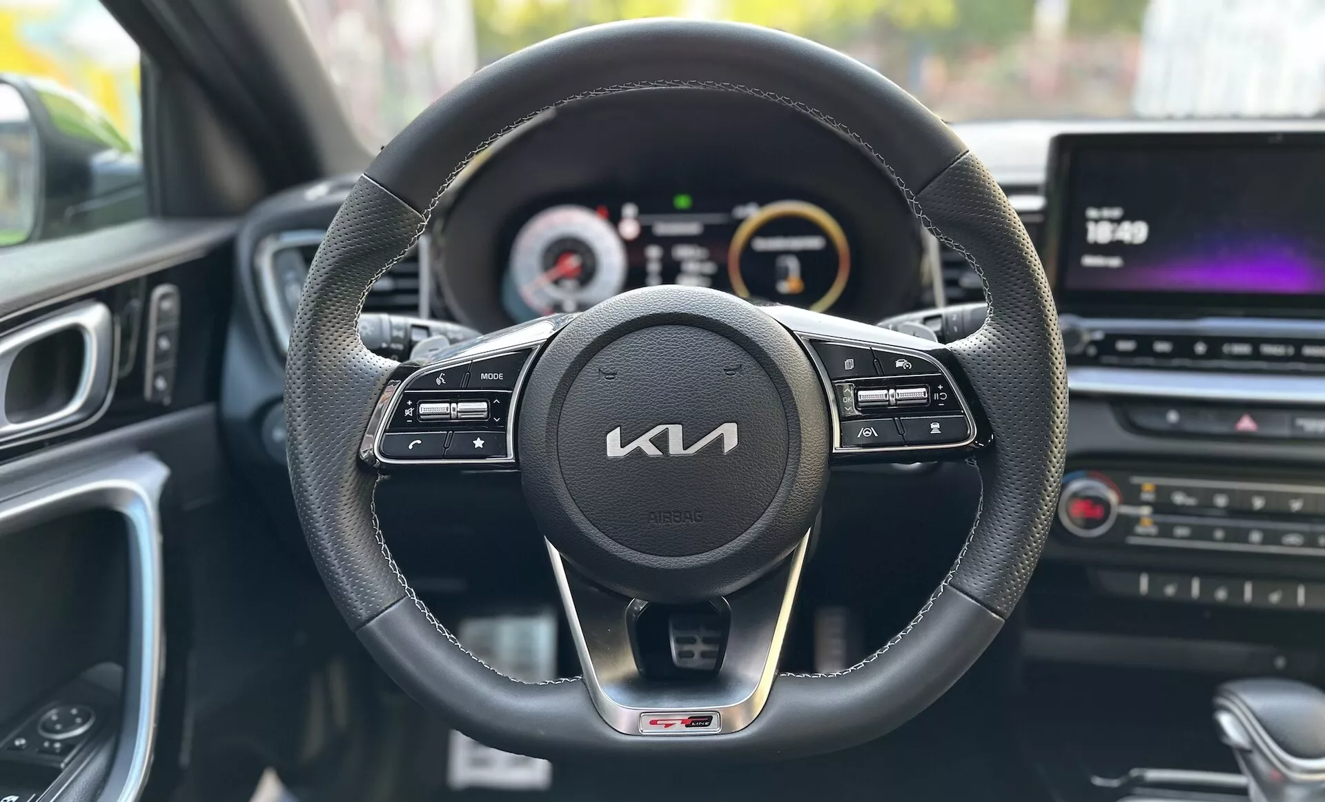 Vue de la perspective du conducteur à l'intérieur d'une Kia Xceed 2022 montrant le tableau de bord, le volant avec boutons de commande, le cluster d'instruments numérique-analogique et la console centrale multimédia