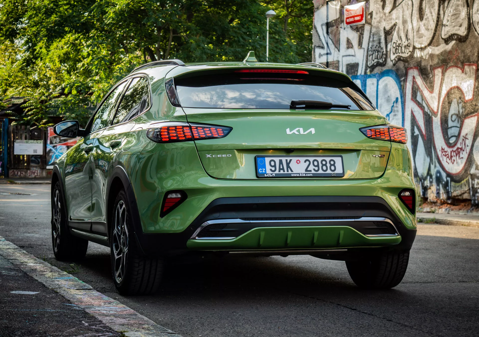 Vue arrière d'un crossover/SUV Kia XCeed vert de 2022 présentant la marque, la conception des feux arrière LED, l'emplacement de la plaque d'immatriculation, l'esthétique du pare-chocs inférieur et la finition brillante dans une rue urbaine.