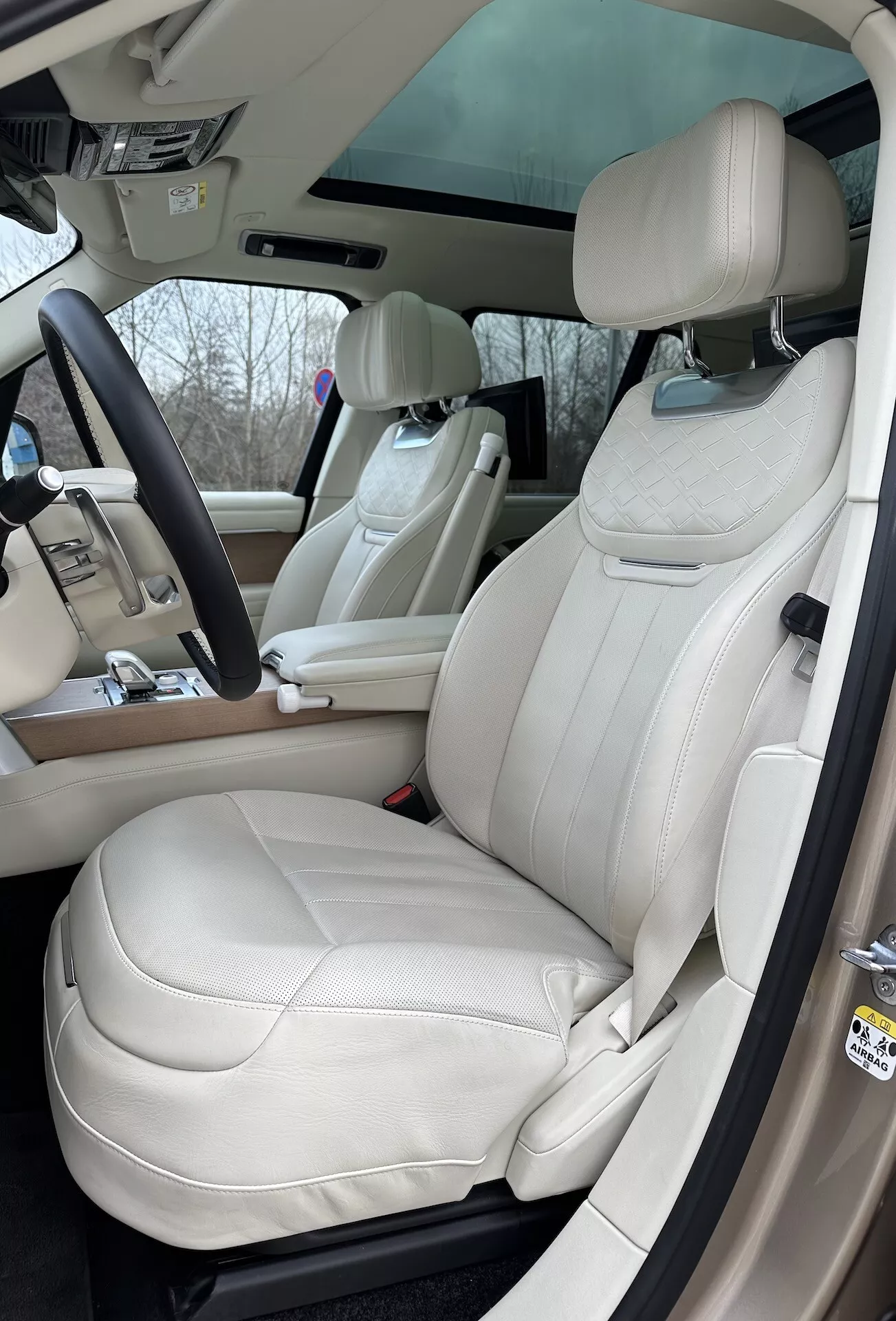 Vue intérieure du Land Rover Range Rover 2021 mettant en évidence le côté conducteur avec sièges en cuir crème de luxe, volant multifonctions et éléments de commande avancés sur la console centrale