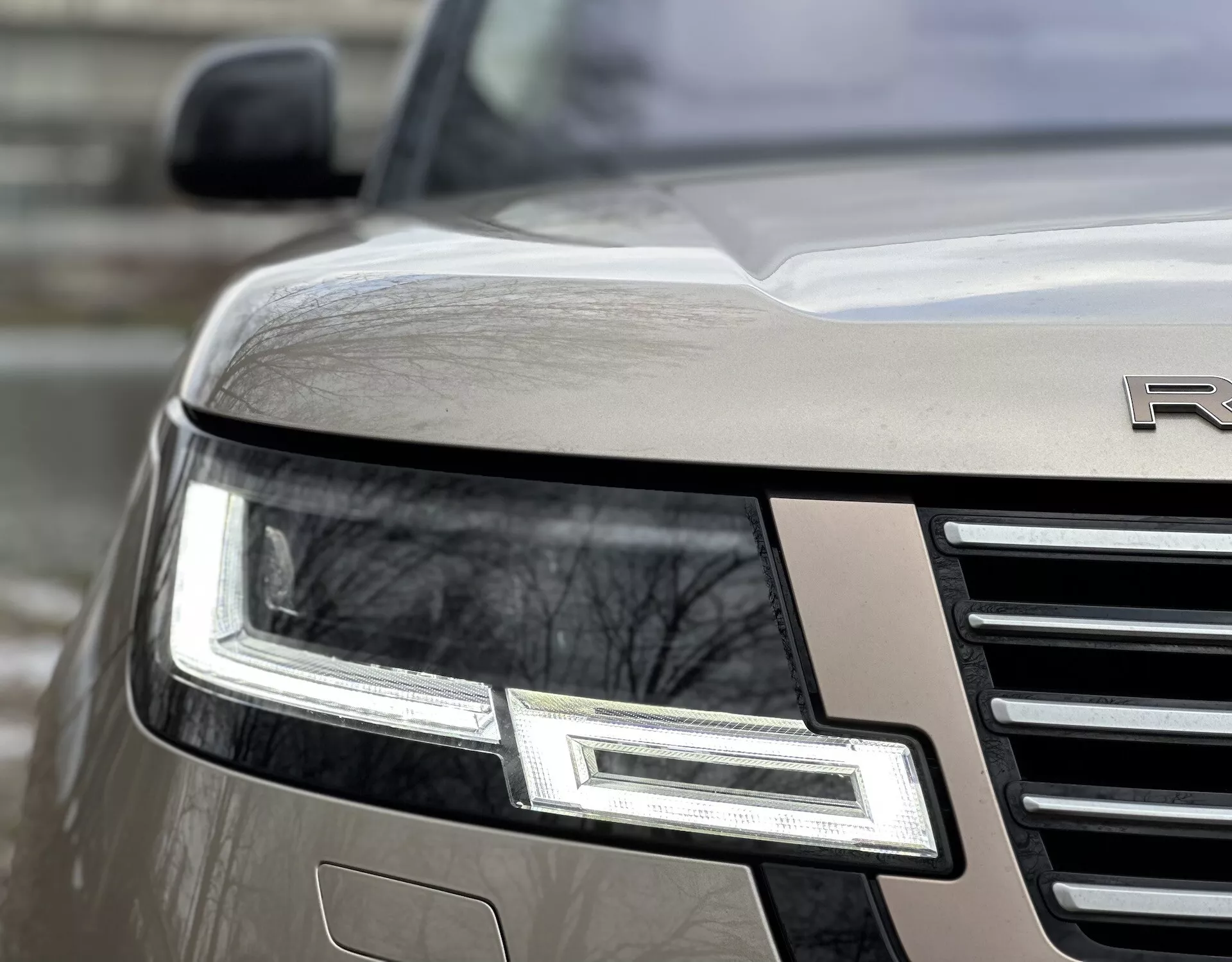 Vue en angle rapproché du coin avant du Land Rover Range Rover 2021 mettant en évidence l'ensemble phare LED, la grille chromée et l'emblème partiel sur une carrosserie métallique