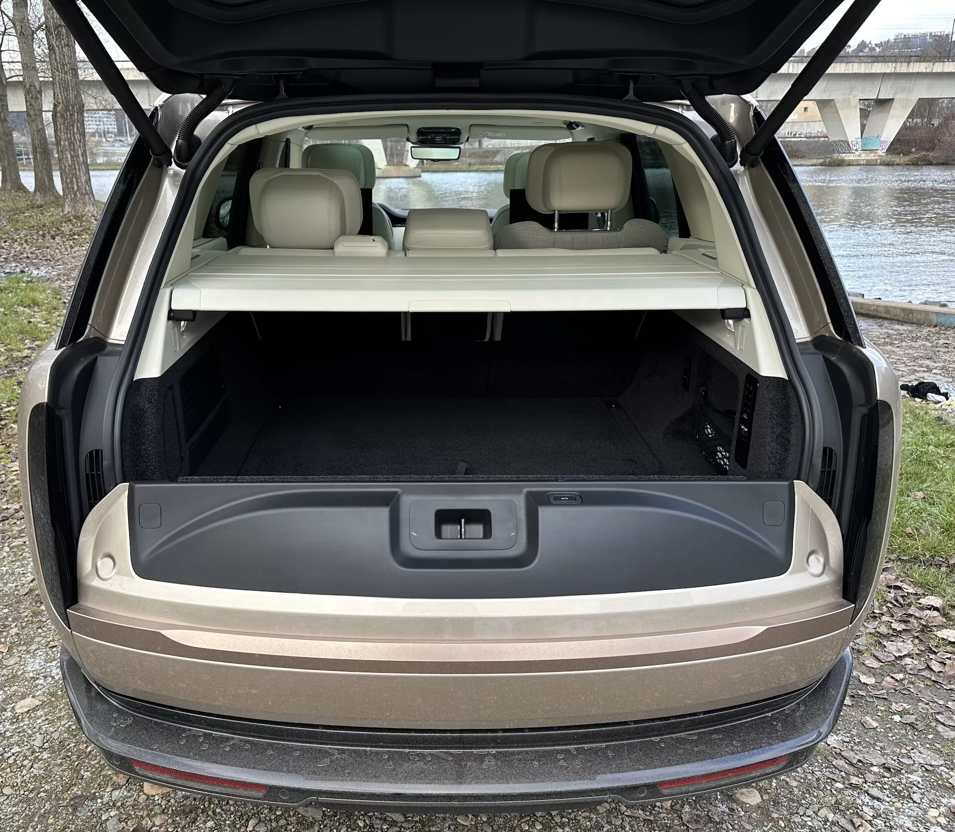 Vue arrière du Land Rover Range Rover 2021 avec hayon ouvert montrant un espace de chargement spacieux, éclairage avancé, et prise de 12 volts dans un cadre de lumière naturelle en extérieur