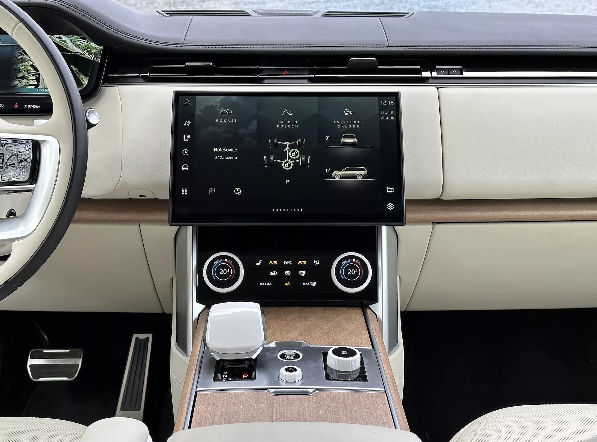 Land Rover Range Rover 2021 avec intérieur moderne, mettant en avant la console centrale et le système d'infodivertissement avec écran tactile haute résolution, grilles d'aération avec accents chromés, contrôle climatique bi-zone, bouton de commande rotatif pour la navigation dans le système et sièges de luxe en cuir bicolore avec finitions en bois.