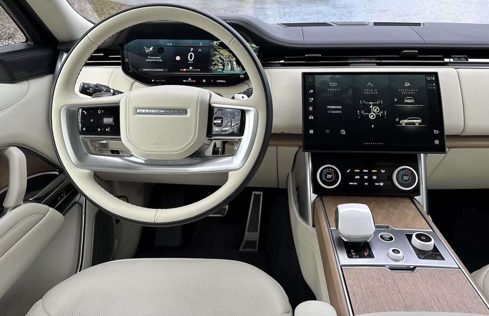 Vue intérieure du Land Rover Range Rover 2021 montrant le volant moderne avec boutons multifonctions, tableau de bord numérique, grand écran tactile central pour l'infodivertissement, contrôle automatique du climat et design de cabine bicolore haut de gamme