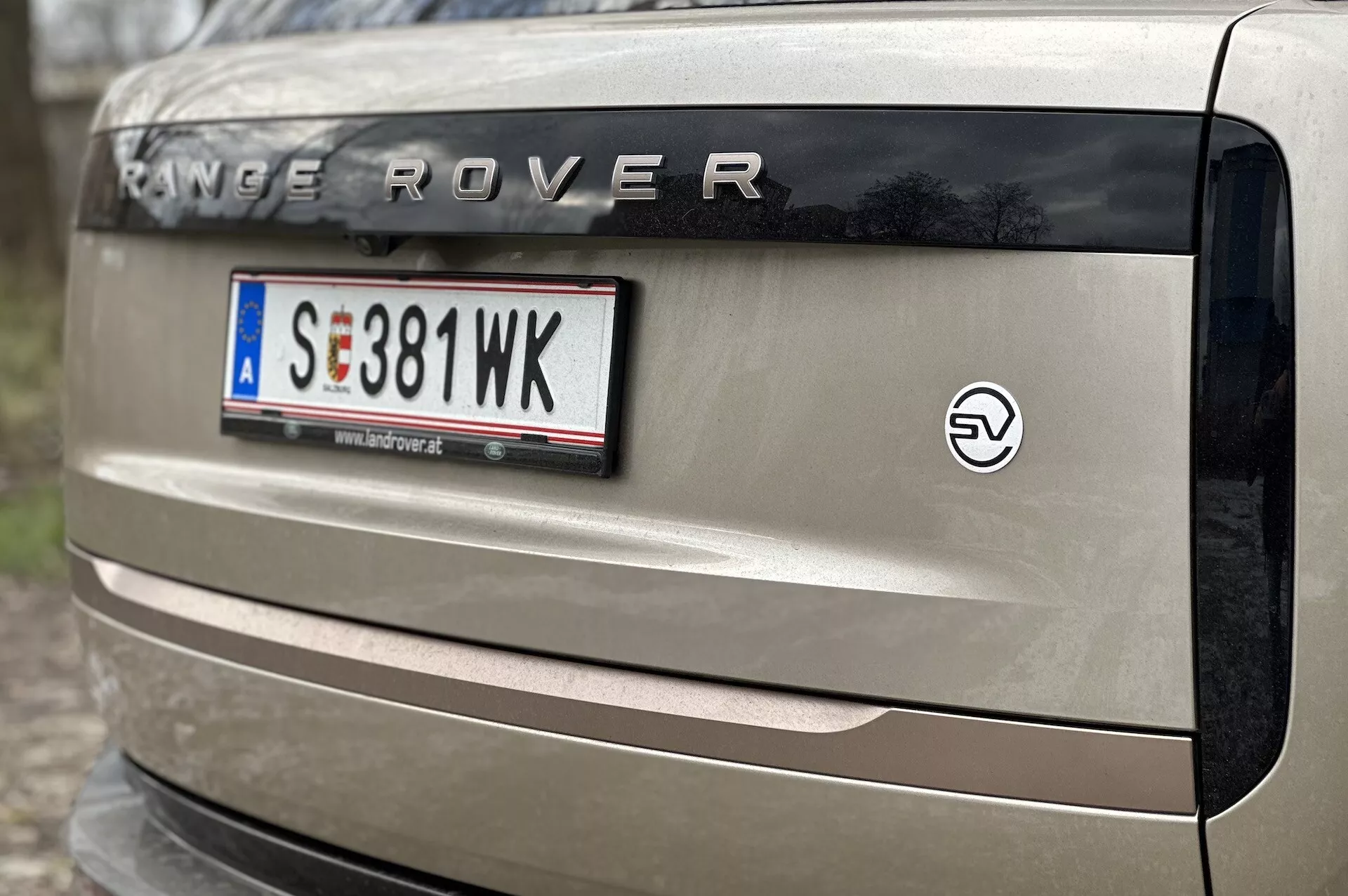 Vue rapprochée du hayon d'un Range Rover 2021 affichant la marque 'RANGE ROVER', plaque d'immatriculation style européen, emblème EV, et partiellement le feu arrière