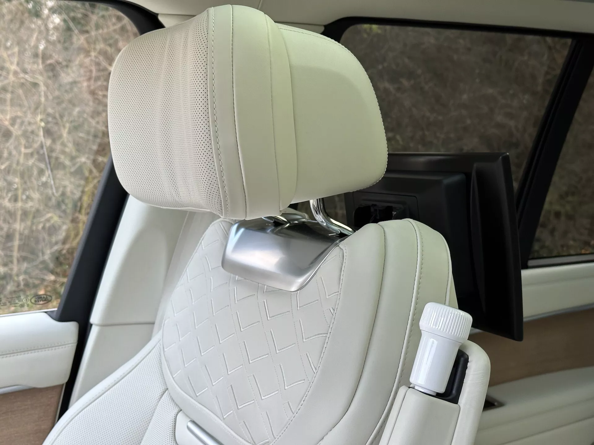 Vue intérieure de la Land Rover Range Rover 2021 mettant en évidence le siège passager en cuir crème matelassé avec support pour la tête en chrome et porte-bouteille côté porte, montrant la conception de véhicule de luxe et les fonctionnalités de confort