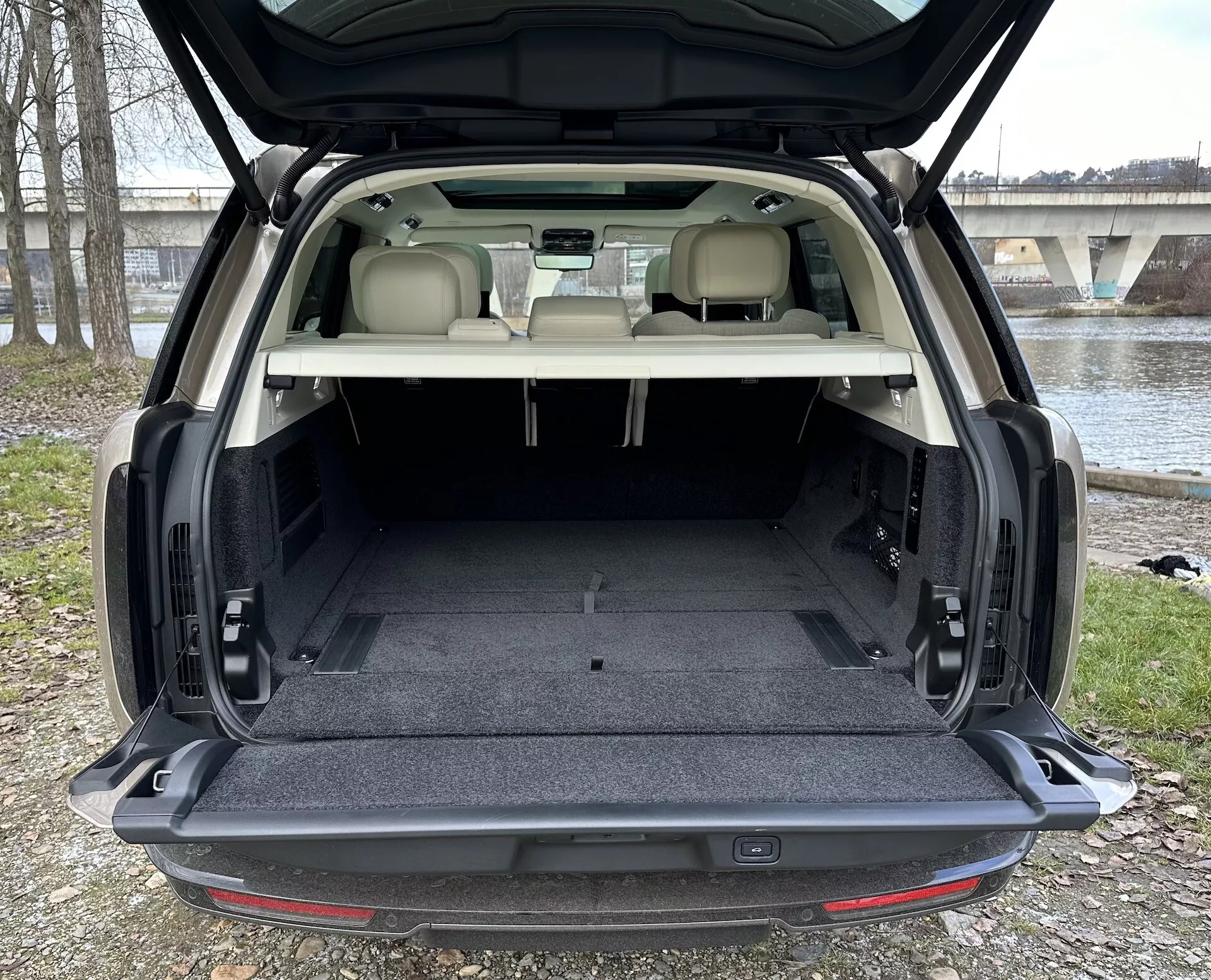 SUV Land Rover Range Rover 2021 montrant un vaste espace de chargement arrière avec hayon ouvert, une garniture de couleur claire contrastant avec un tapis sombre et des caractéristiques intérieures comprenant un éclairage de l'espace de chargement et des mécanismes de pliage de sièges possibles