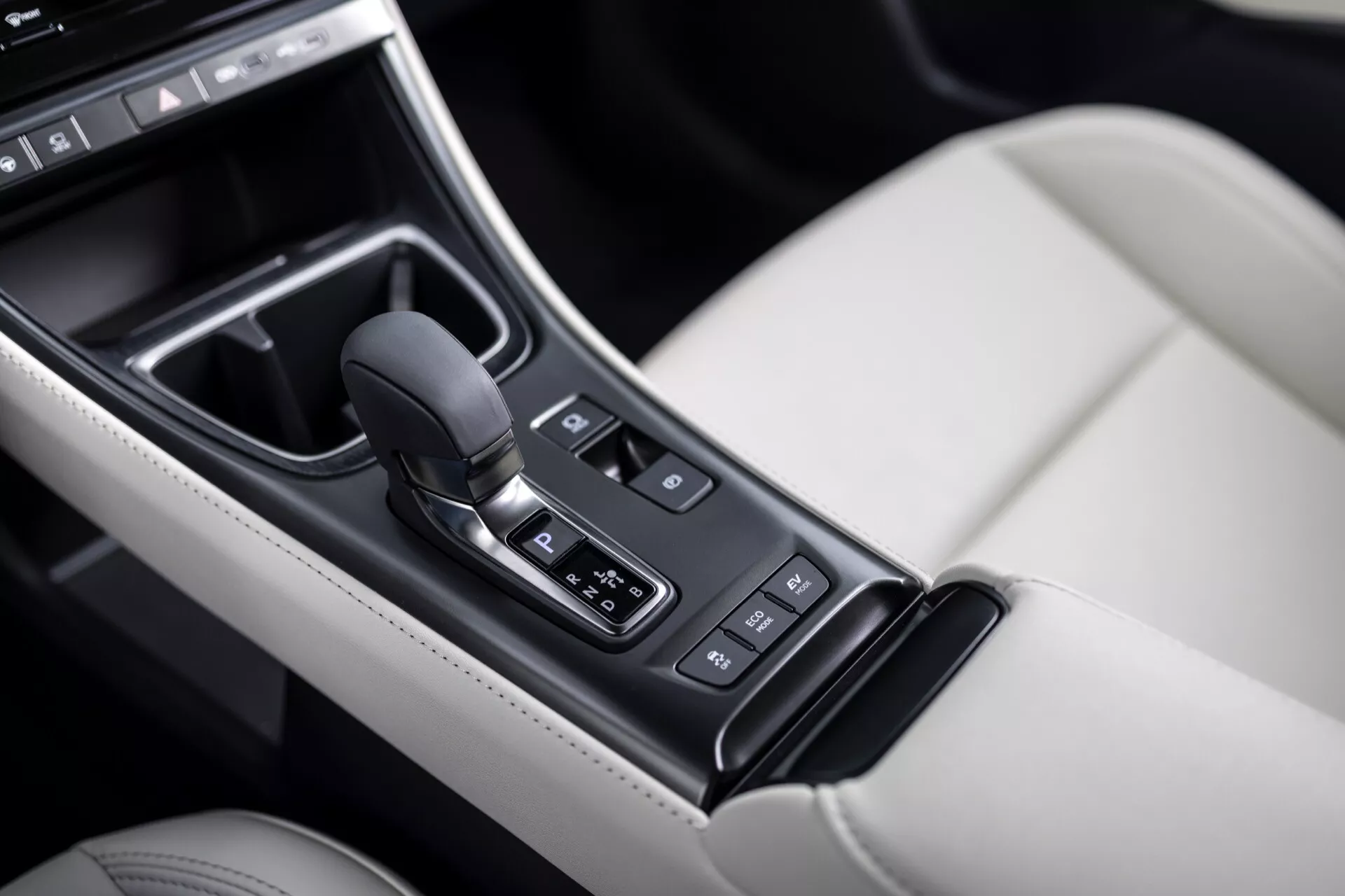 Console centrale de la Lexus LBX 1ère génération 2024 présentant le levier de vitesse automatique, les commandes des modes de conduite, et les finitions intérieures luxueuses