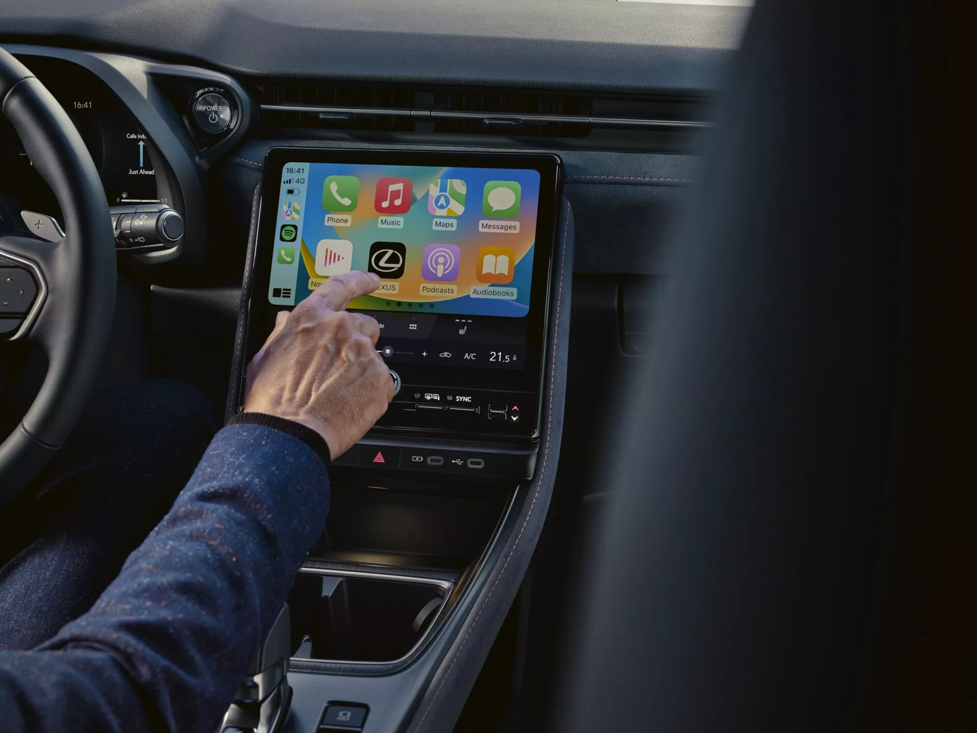 Vue rapprochée à l'intérieur d'un Lexus LBX 2024 mettant en vedette le système d'infodivertissement du point de vue du passager, affichant des applications de connectivité et des réglages de contrôle climatique sur un écran tactile vertical