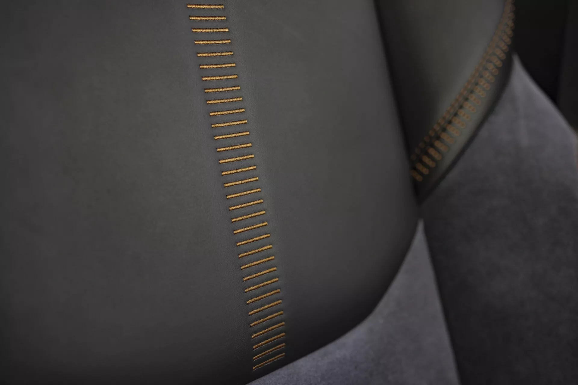 Vue rapprochée des dents de fermeture éclair de haute qualité avec couture détaillée sur tissu lisse, ressemblant à du suède et finition métallique dorée réfléchissant la lumière