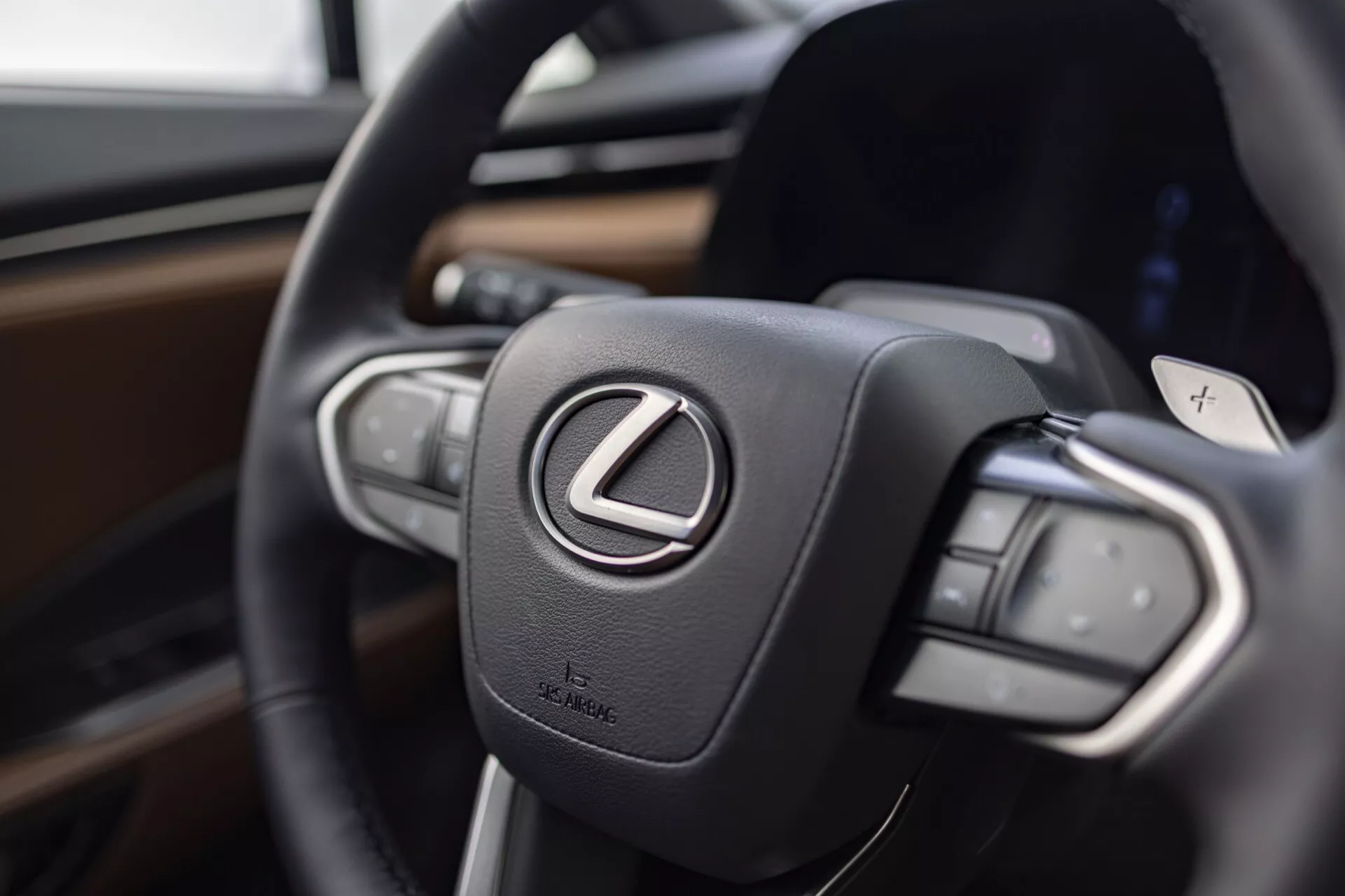 Vue rapprochée du volant du Lexus LBX 2024 mettant en évidence le logo Lexus et les boutons de commande, accentuant le luxe et la technologie avancée