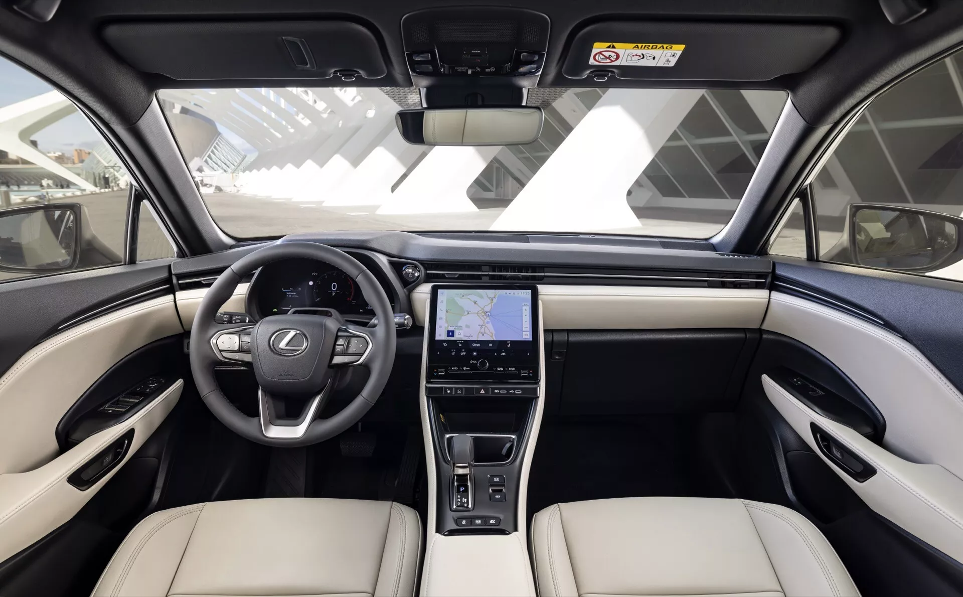 Vue centrale avant de l'intérieur du Lexus LBX 2024 avec tableau de bord bicolore, volant multifonctions à trois branches, grand écran d'infodivertissement avec GPS et sièges haut de gamme beige