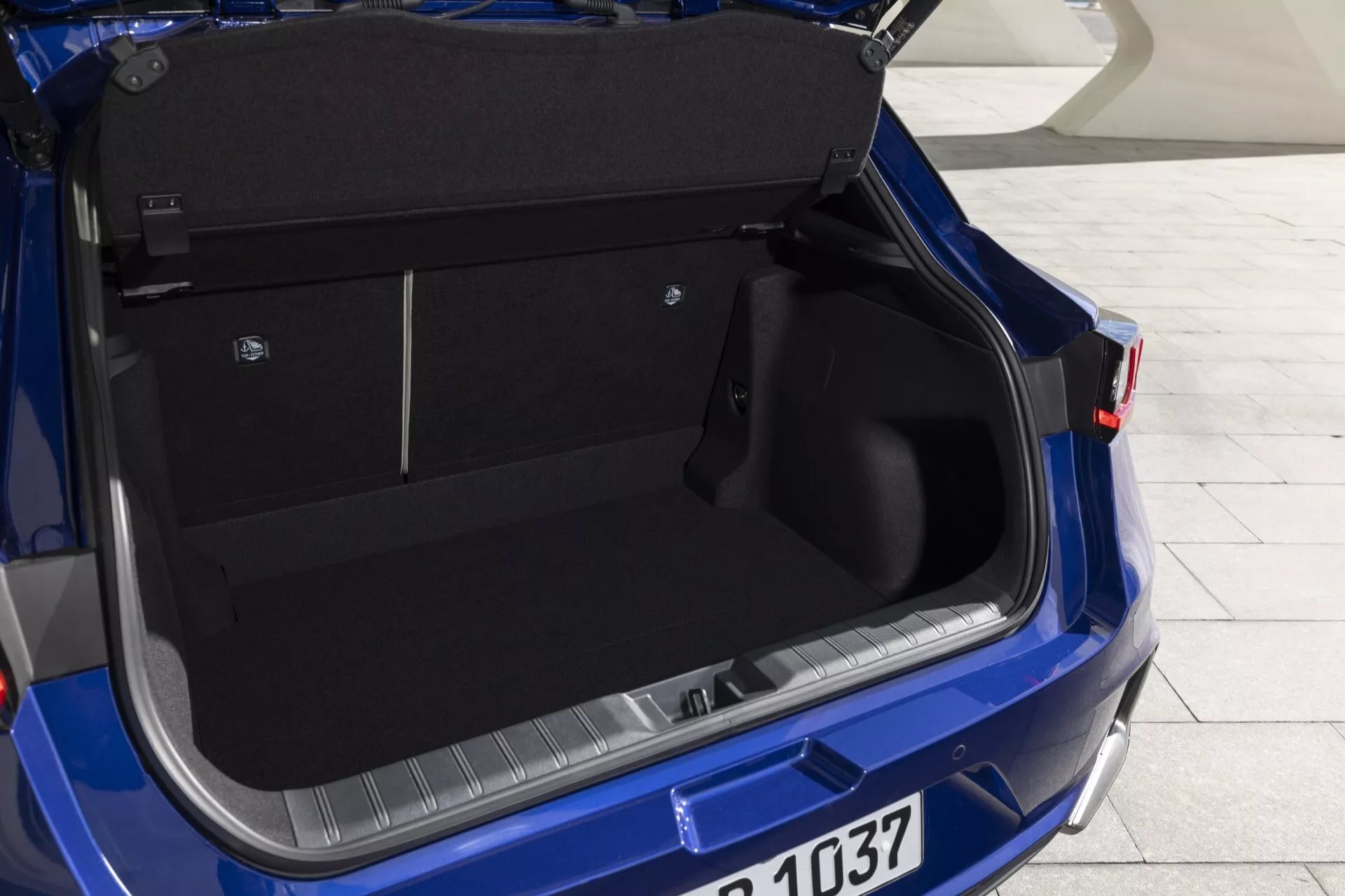 Vue rapprochée de l'espace coffre spacieux de la Lexus LBX 2024 bleue avec le couvercle ouvert, montrant les détails intérieurs et les caractéristiques de conception depuis une perspective arrière droite