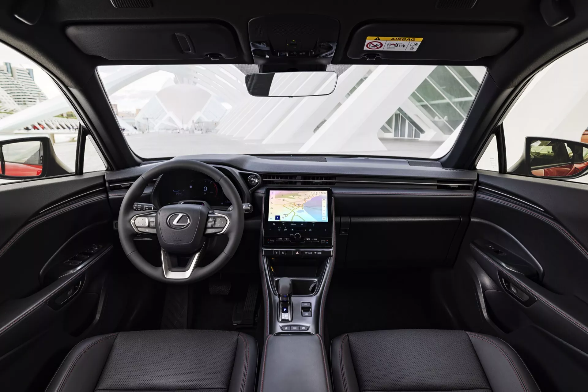 Vue intérieure de la Lexus LBX 1ère génération 2024 depuis le siège arrière central montrant le tableau de bord, le volant, les sièges avant en cuir et les fonctionnalités high-tech