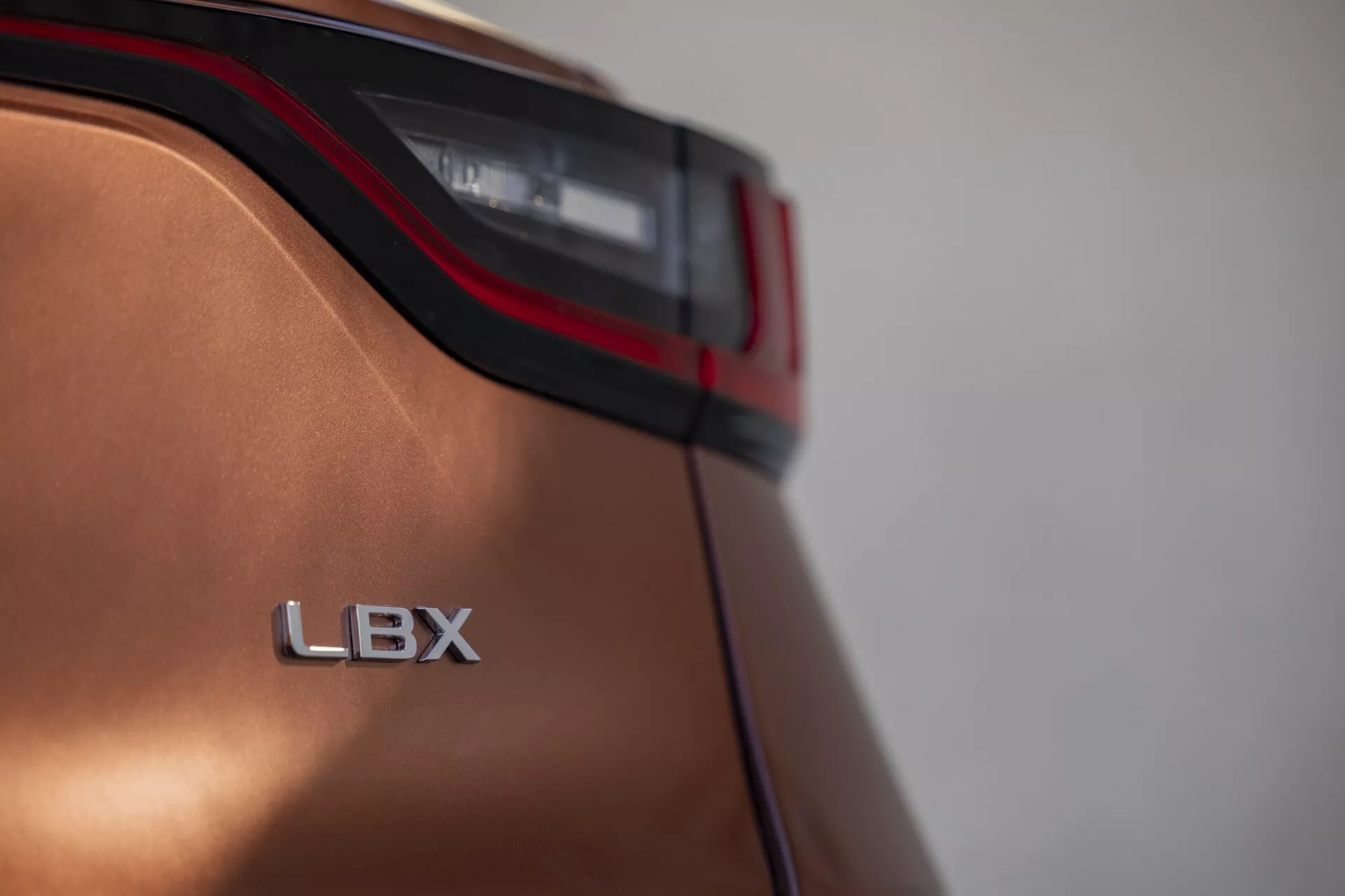Gros plan sur le quart arrière du Lexus LBX 2024 montrant le détail du feu arrière LED et l'insigne LBX avec finition métallique et design aérodynamique