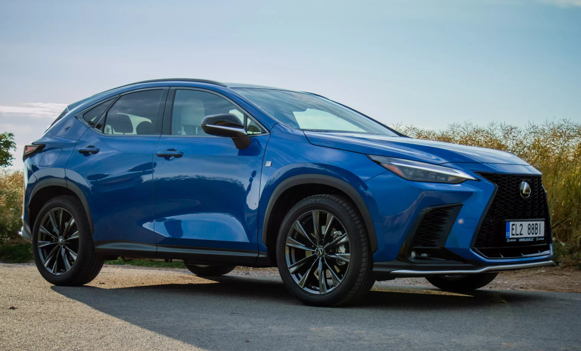 SUV compact Lexus NX 2021 en bleu vif, montrant le pare-chocs avant, la grille, les phares LED, le capot, les roues et les lignes de contour latérales depuis une vue de trois quarts avant à l'extérieur en plein jour