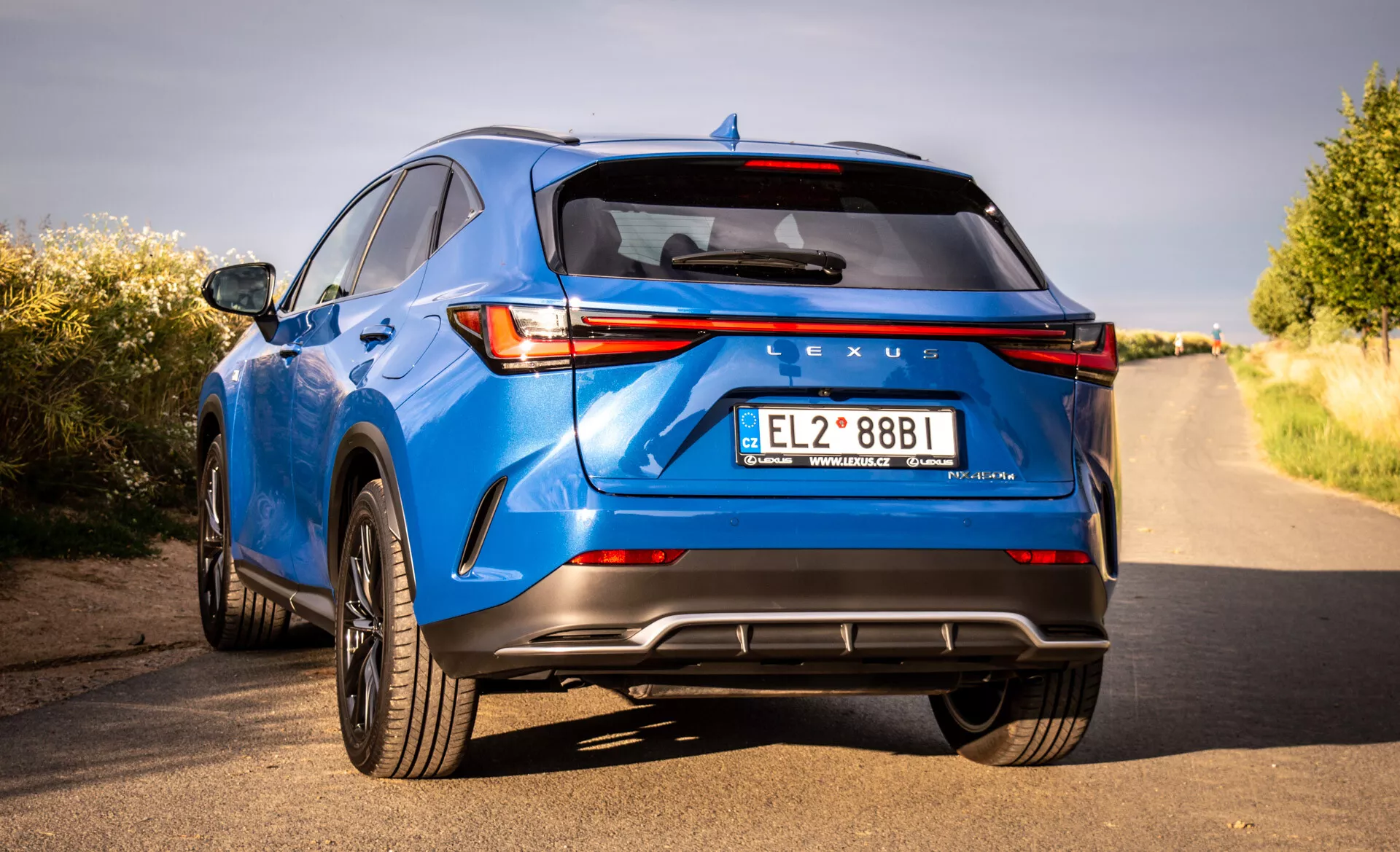 Vue arrière d'un SUV crossover de luxe Lexus NX bleu 2021 présentant des feux arrière LED, marque Lexus, pare-chocs arrière sportif avec diffuseur, doubles tuyaux d'échappement et autres caractéristiques technologiques et de design depuis une perspective basse de trois quarts