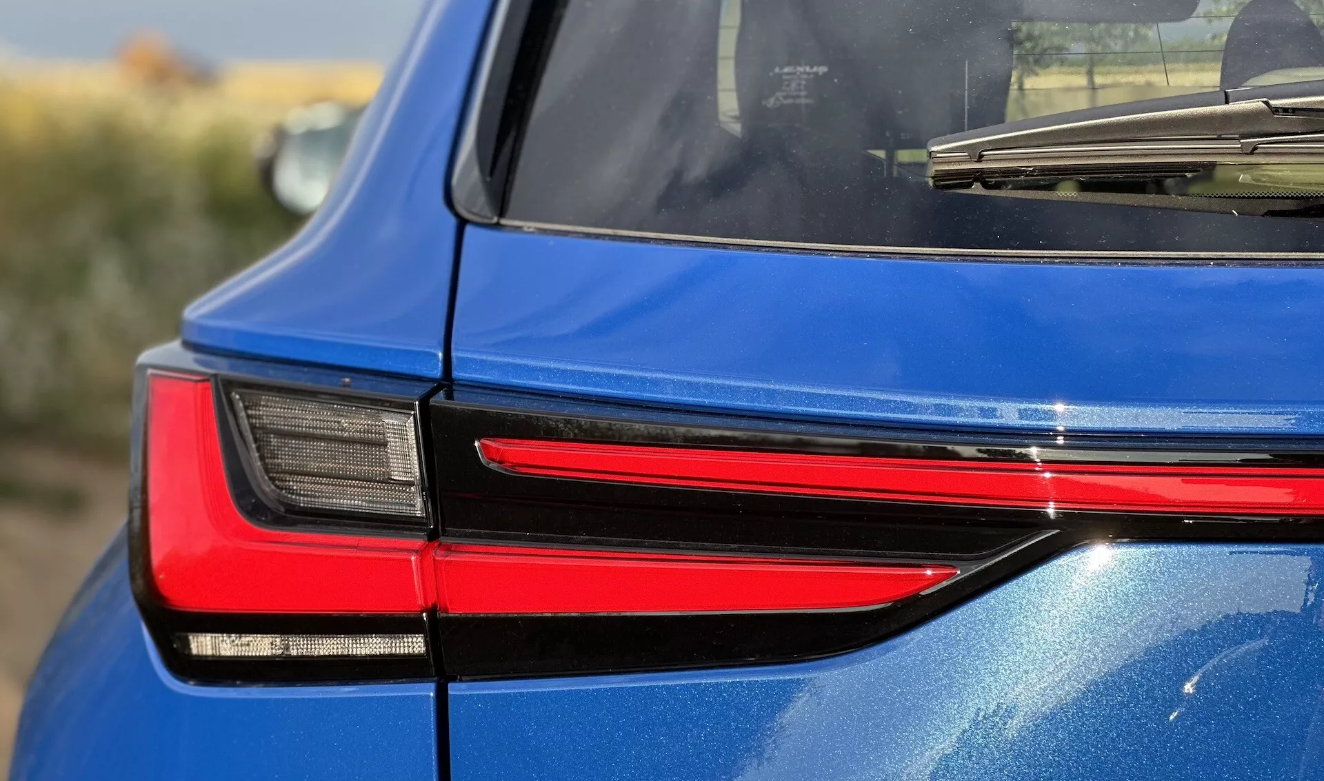 Vue détaillée de l'arrière droit d'une Lexus NX 2021, mettant en évidence la conception moderne du feu arrière LED, reflétant sa technologie d'éclairage sophistiquée et sa finition bleue brillante.
