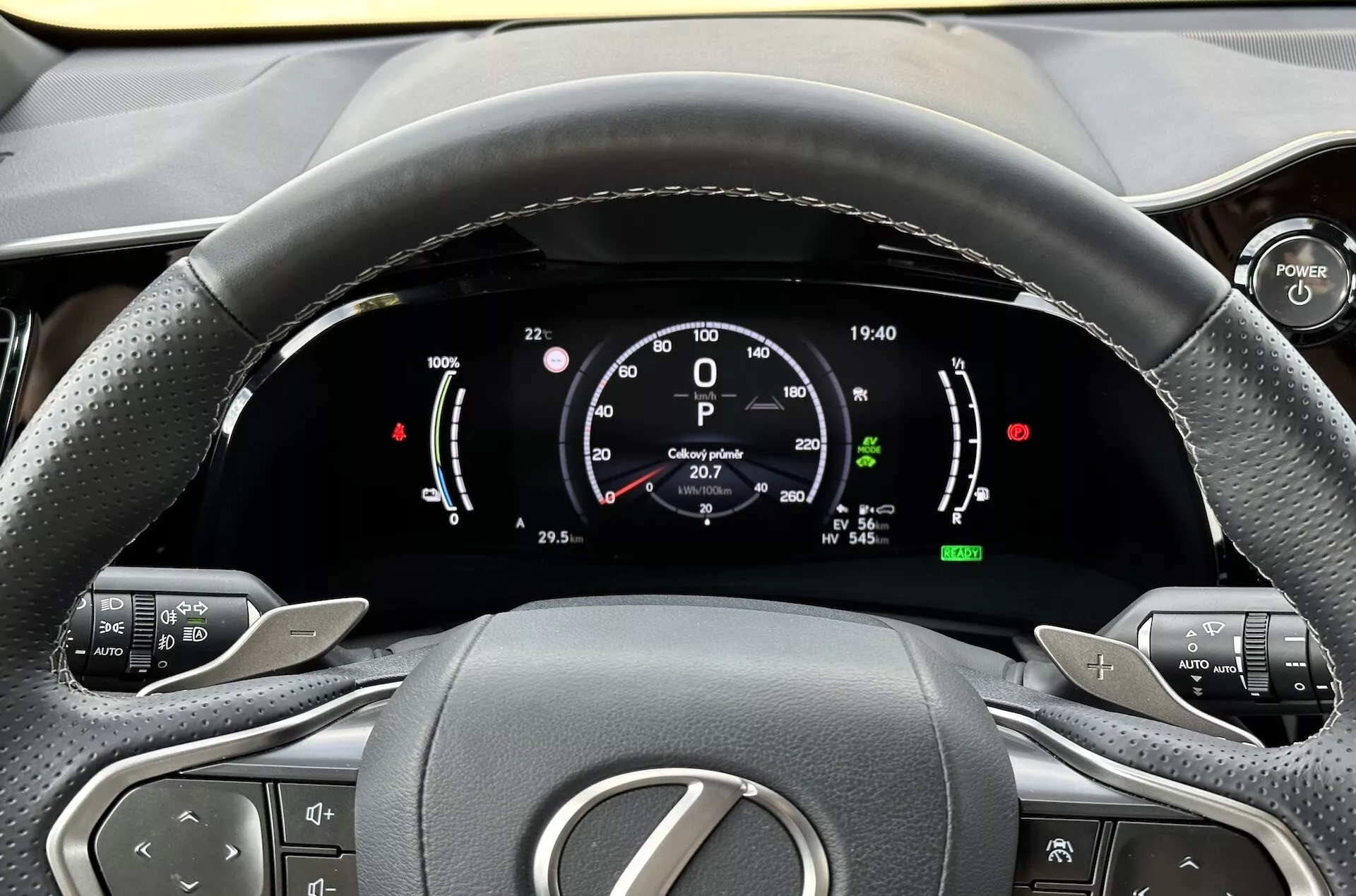 Vue depuis le siège du conducteur sur le volant et le tableau de bord numérique du Lexus NX 2021, mettant en évidence les indicateurs de la technologie hybride, les boutons de contrôle du confort et la conception intérieure ergonomique