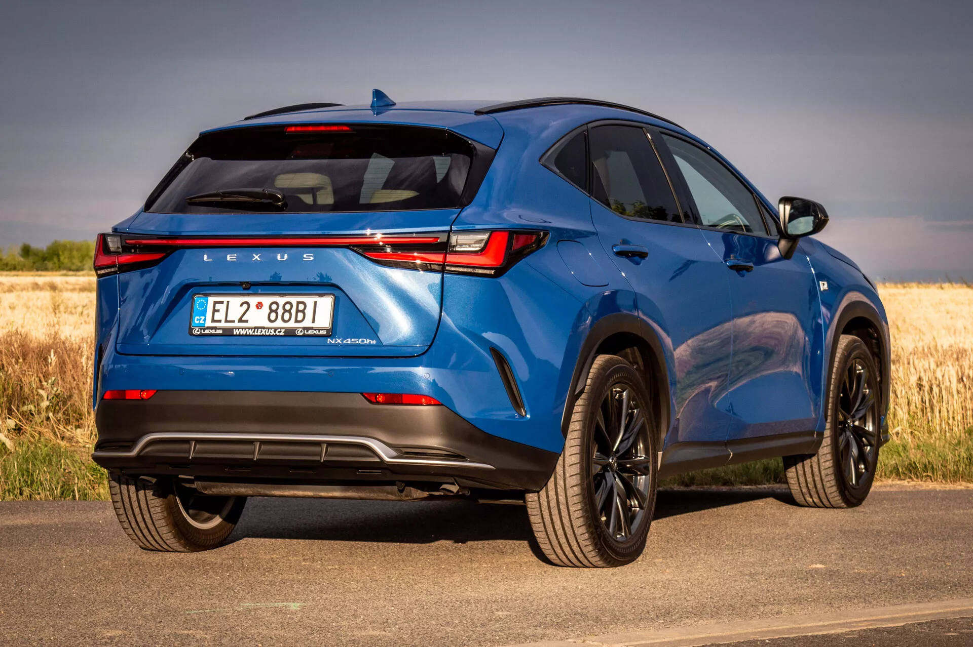 SUV Lexus NX bleu 2021 en vue arrière trois quarts mettant en avant les éléments de design et les caractéristiques technologiques par une journée ensoleillée avec un arrière-plan naturel