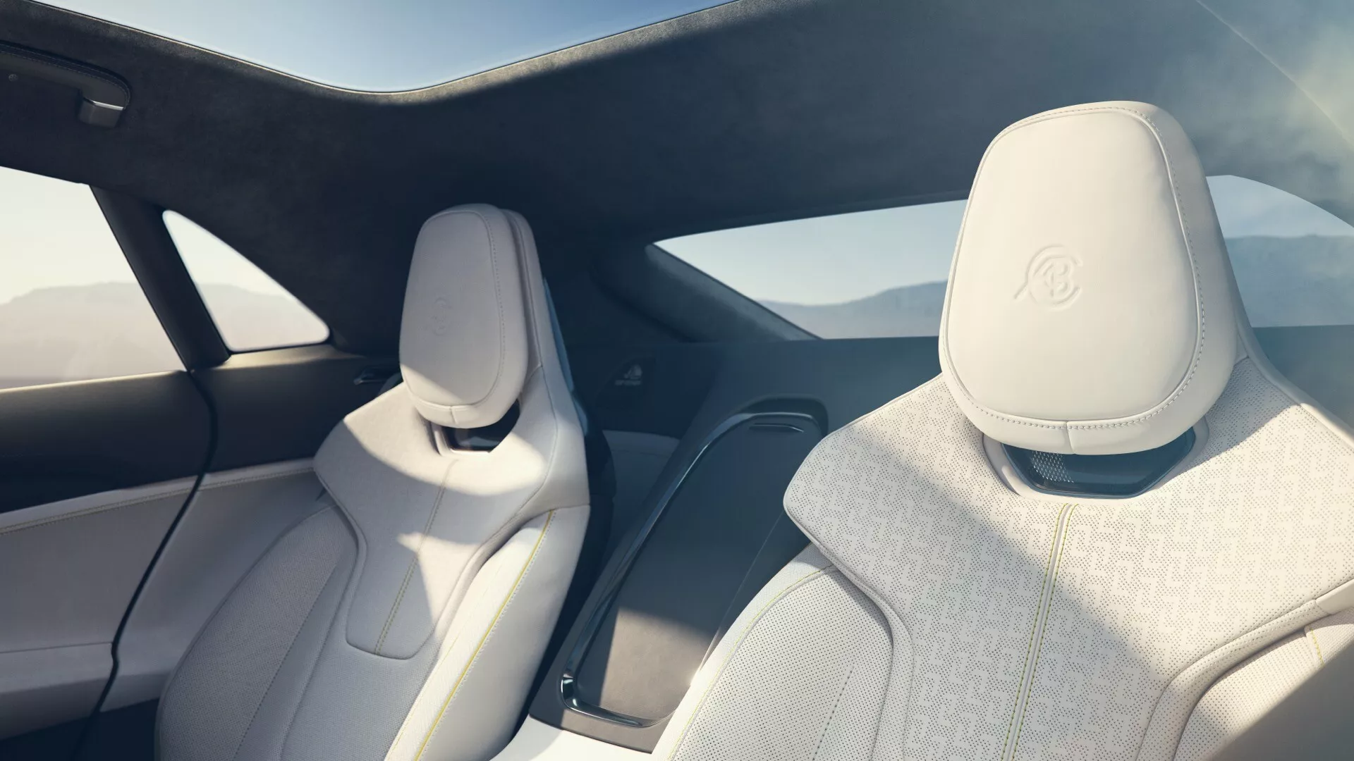 Intérieur de la Lotus Emeya de première génération 2024 présentant des sièges en cuir blanc avec logo de marque premium, vue panoramique sur les fenêtres latérales et arrière, conception spacieuse avec potentiellement un toit en verre, matériaux intérieurs de haute qualité avec accents métalliques et brillants, et un éclairage ambiant chaleureux