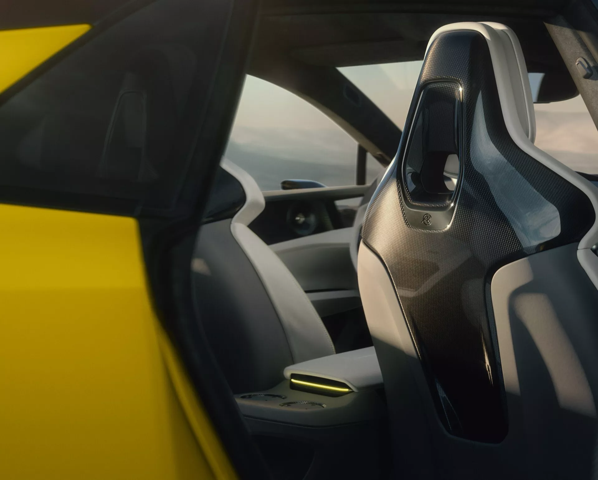 Vue rapprochée de l'intérieur de la Lotus Emeya 2024, se concentrant sur le côté conducteur, présentant des commandes montées sur la porte, un volant en fibre de carbone, un tableau de bord numérique et un schéma de couleurs bicolore