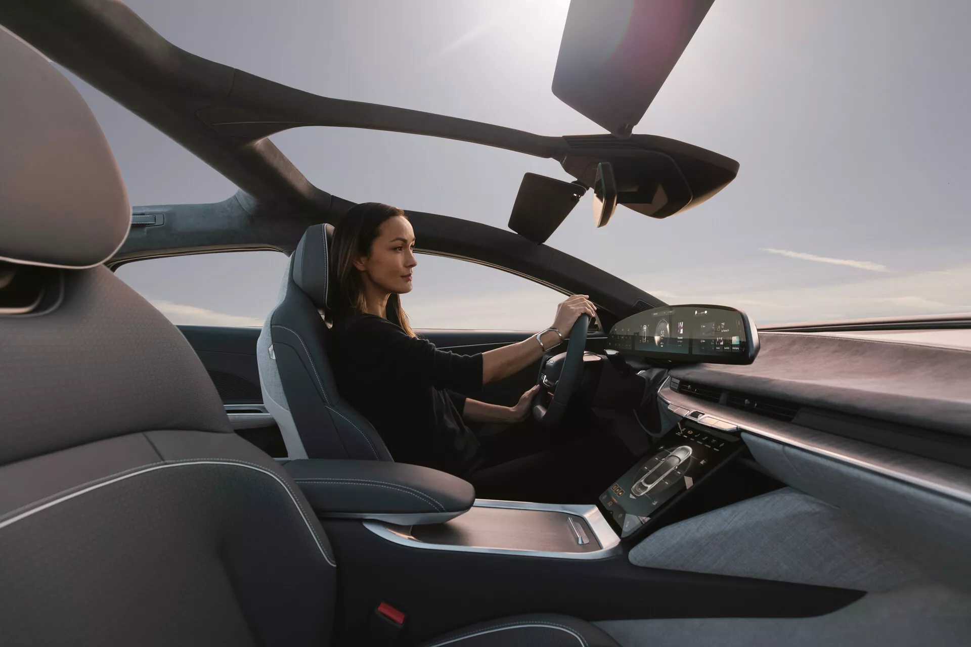 Vue intérieure de la Lucid Air 2022 depuis le côté passager, montrant le siège du conducteur moderne et le tableau de bord avancé avec écrans digitaux et commandes tactiles, mettant en avant un design luxueux et technologiquement avancé