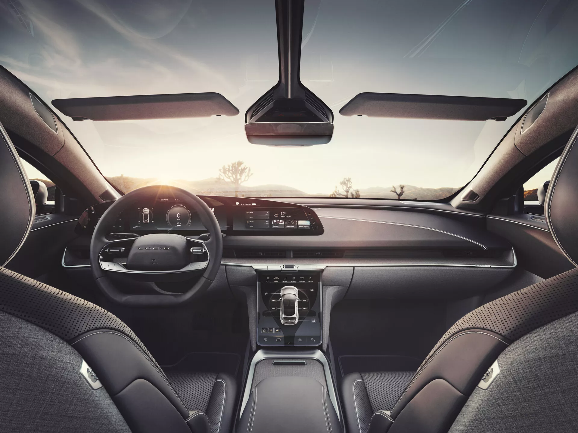 Vue intérieure d'une voiture Lucid Air 2022 depuis le siège arrière, montrant le tableau de bord, l'écran d'infodivertissement, le tableau de bord numérique et les matériaux en cuir et de qualité supérieure, indiquant un modèle haut de gamme avec un système multimédia avancé, des commandes de climatisation et des technologies de connectivité.