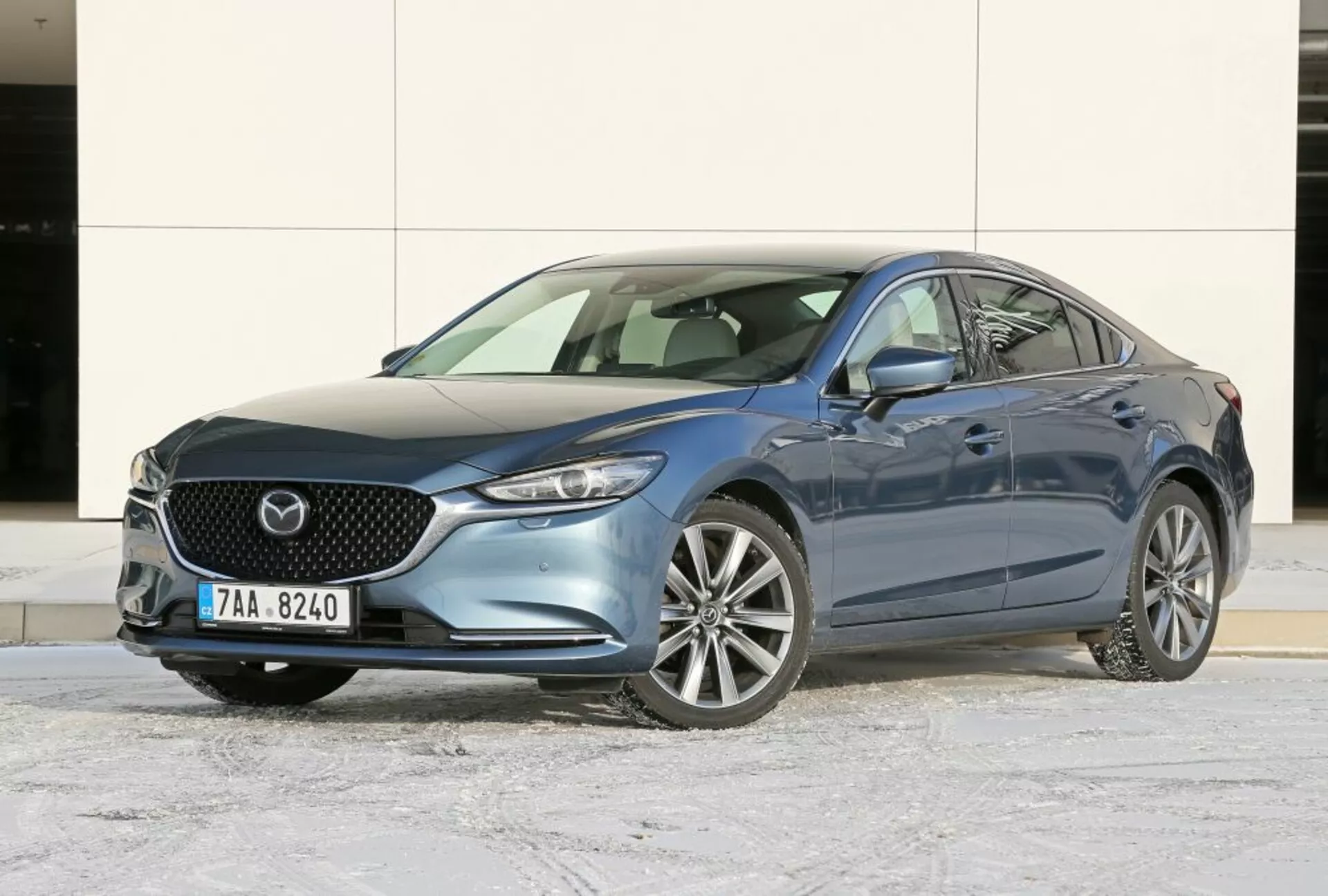 Sedan Mazda 6 2013 en bleu, présentant un angle avant de trois quarts pour une vue claire de la grille avant, de l'emblème, des phares élégants et des roues en alliage sur du bitume hivernal