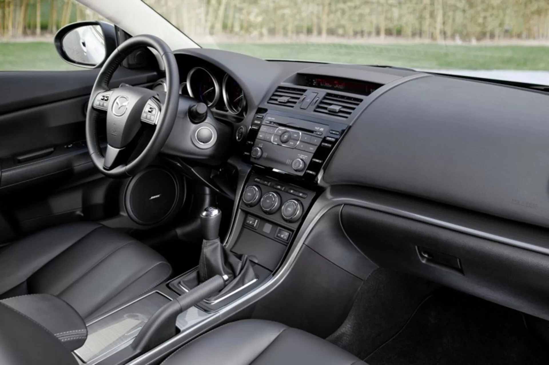 Intérieur de la berline Mazda 6 de 2008 montrant le cockpit du conducteur et la vue du tableau de bord du passager avec commandes au volant, systèmes d'infodivertissement et de contrôle climatique, et console de transmission automatique, mettant en avant le design moderne et les caractéristiques technologiques de la voiture.