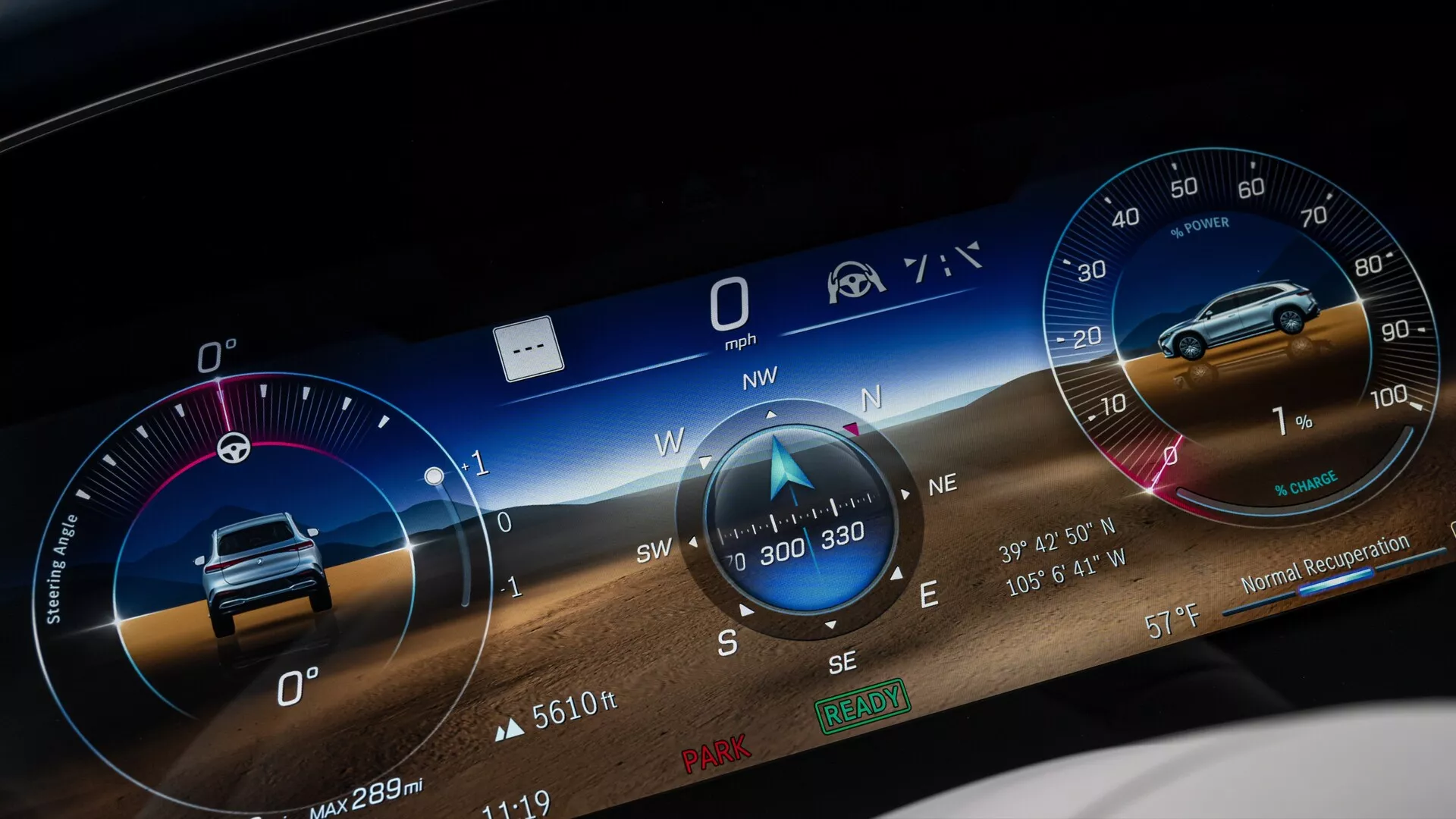 Gros plan du tableau de bord numérique de la Mercedes EQS SUV 2022, présentant une interface utilisateur graphique en écran large affichant diverses mesures telles qu'un compteur de vitesse à 0 mph, une boussole pointant vers le nord-ouest, possiblement un compteur de tours, des informations sur le kilométrage comme 'Max 289m' et des icônes pour le rappel de la ceinture de sécurité et l'assistance à la conduite. Le fond inclut un paysage dynamique pour l'attrait visuel.