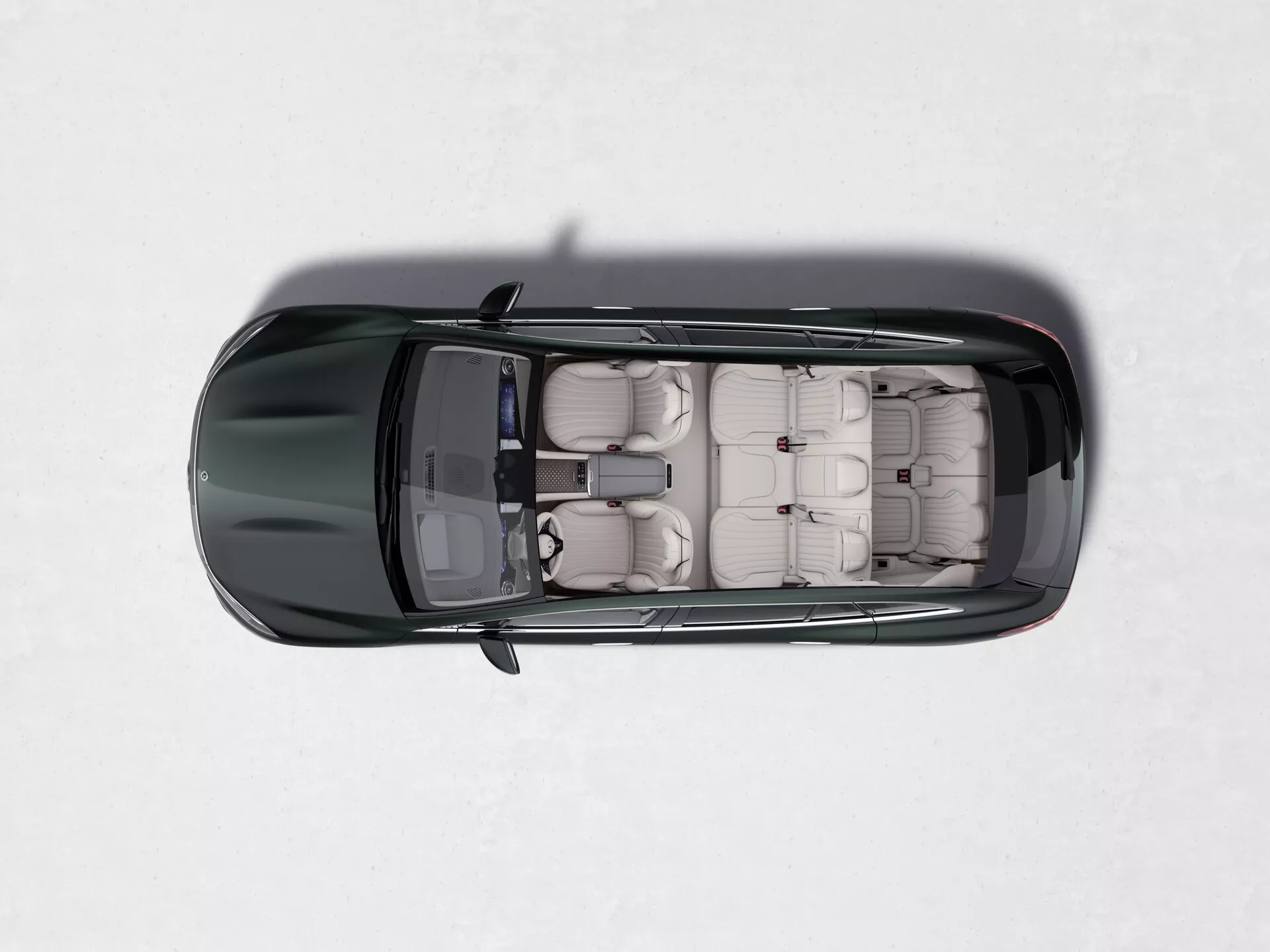 Vue du dessus d'un Mercedes EQS-SUV 2022 de couleur sombre sur une surface claire et enneigée. L'image montre le toit ouvrant entièrement ouvert, révélant l'intérieur en cuir beige ou brun avec une disposition des sièges en trois rangées, mettant en évidence sa capacité en tant que véhicule plus grand pour les passagers, probablement un SUV.