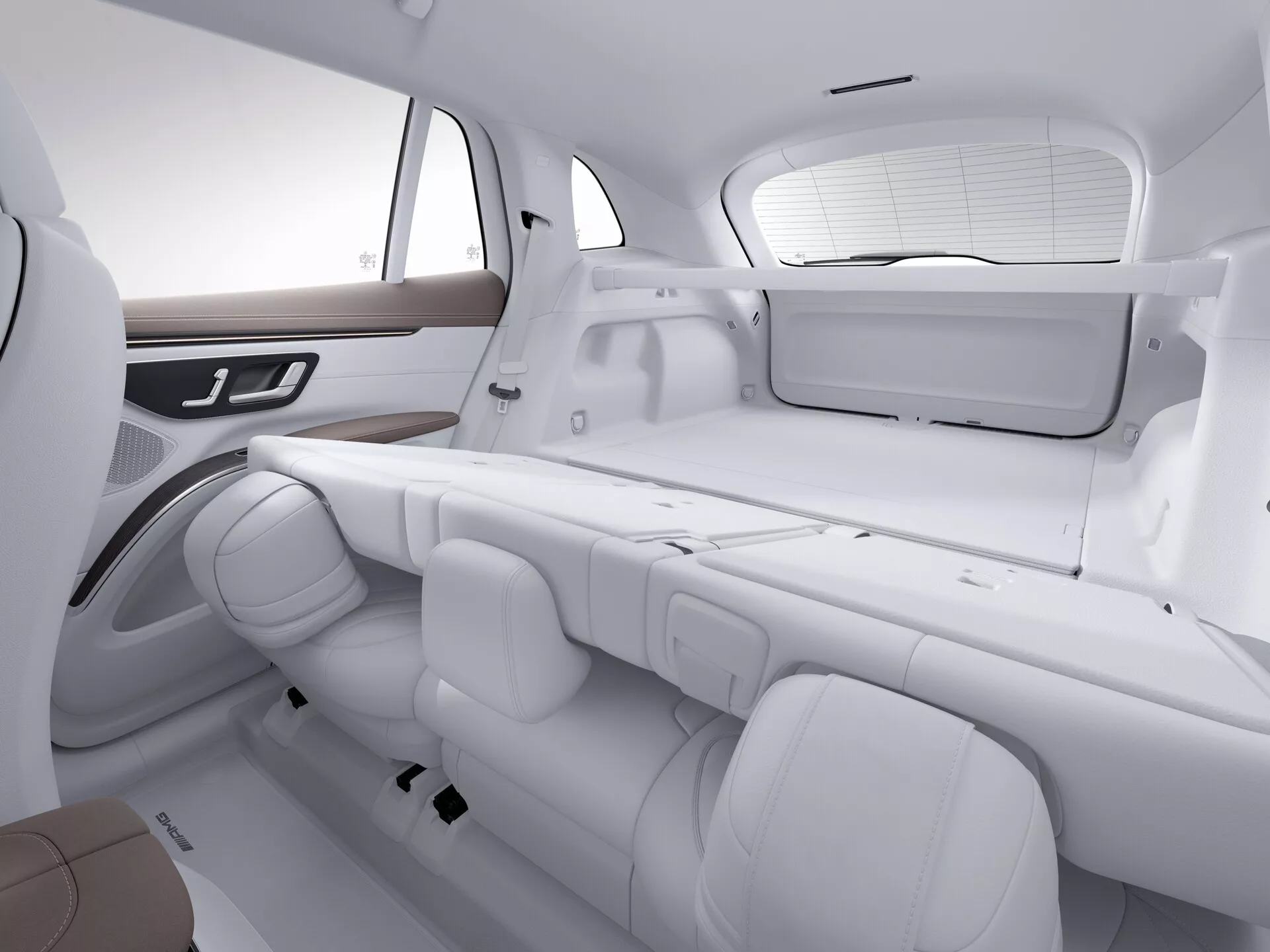 Vue intérieure du Mercedes EQS SUV 2022, se concentrant sur les sièges arrière et une partie du coffre. L'image est prise d'un angle oblique, légèrement au-dessus de la hauteur des sièges, montrant la disposition des sièges et l'espace. Le ton blanc monochromatique met en avant le design propre et moderne. Les sièges arrière sont en configuration banquette avec trois appuie-têtes réglables et ceintures de sécurité individuelles. La porte latérale présente une garniture en bois et des commandes intégrées potentiellement pour les fenêtres ou des fonctions électroniques. La fenêtre arrière est équipée d'un pare-soleil et une tablette plate est également visible, soulignant le confort des passagers et les caractéristiques de luxe.