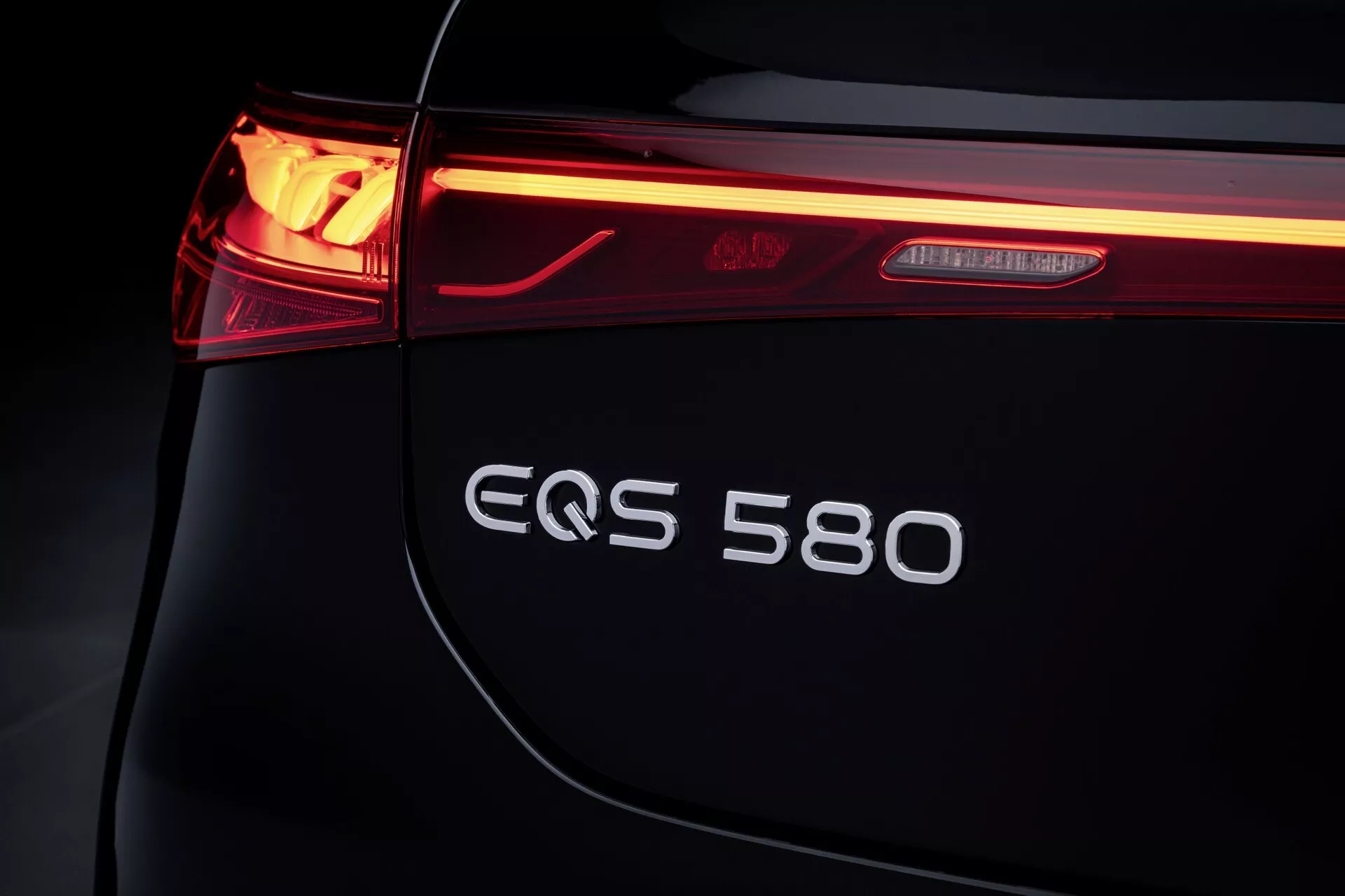 Vue rapprochée de l'arrière gauche d'une Mercedes-Benz EQS 2024, mettant en lumière le feu arrière LED, le badge EQS 580 et le design épuré du coffre, symbole de luxe et d'innovation électrique.