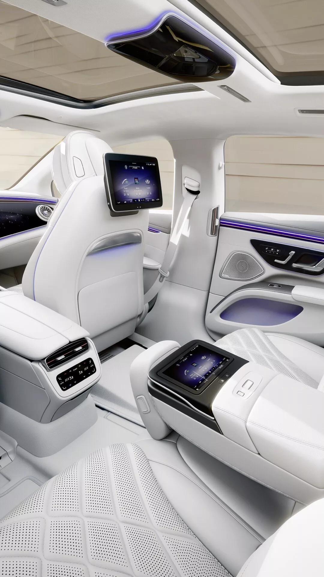 Vue intérieure d'une voiture de luxe Mercedes-Benz EQS 2024 montrant le compartiment passagers arrière avec des sièges spacieux, toit panoramique, sièges en cuir blanc de qualité supérieure avec motif matelassé, écrans de divertissement pour les sièges arrière et fonctionnalités technologiques avancées